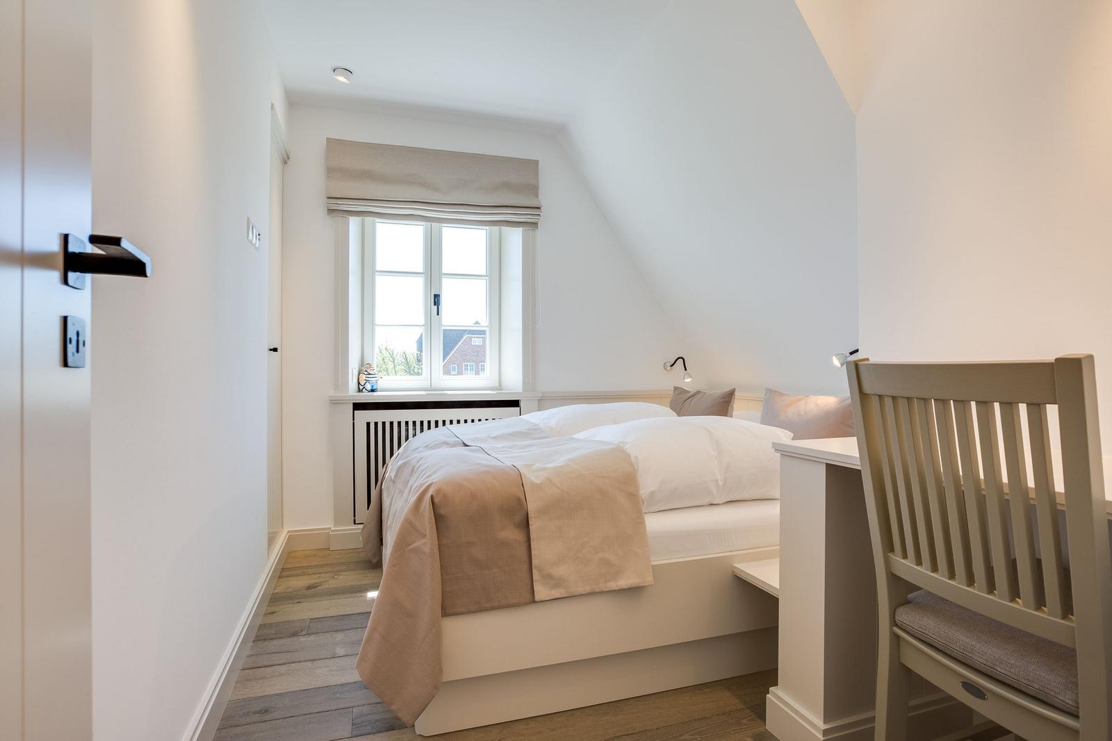 Schlafzimmer mit Bett, Fenster und Schreibtisch