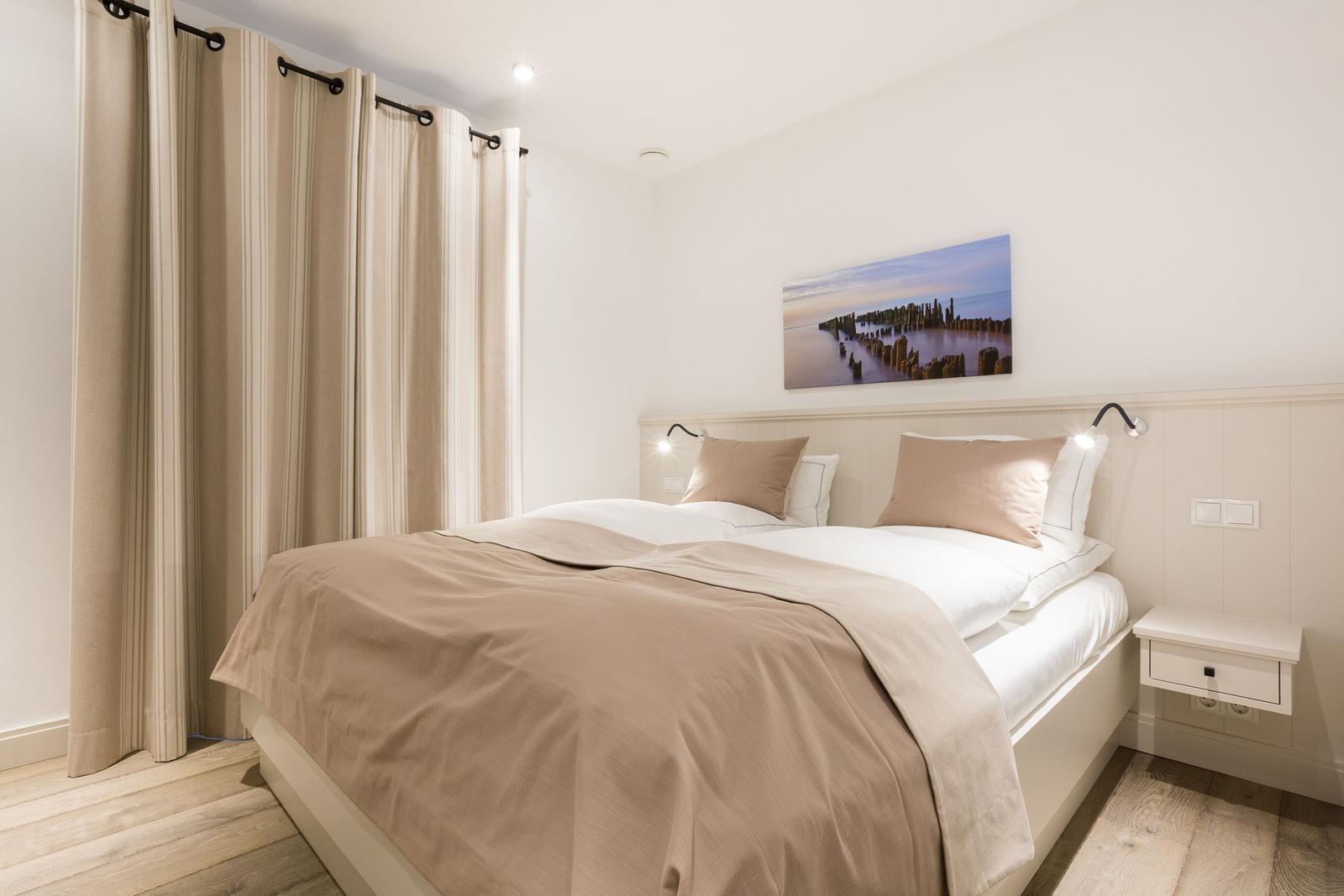 Schlafzimmer mit Doppelbett, Vorhängen und Wandbild.