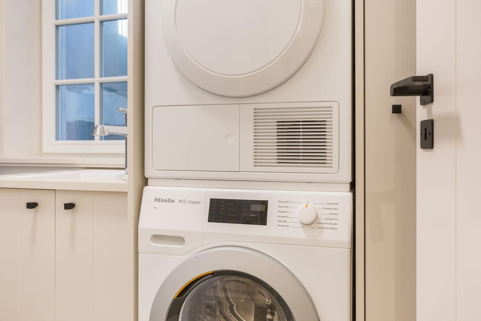 Wäschetrockner und Waschmaschine in weißer Ausführung. Fenster und Schrank sind sichtbar.