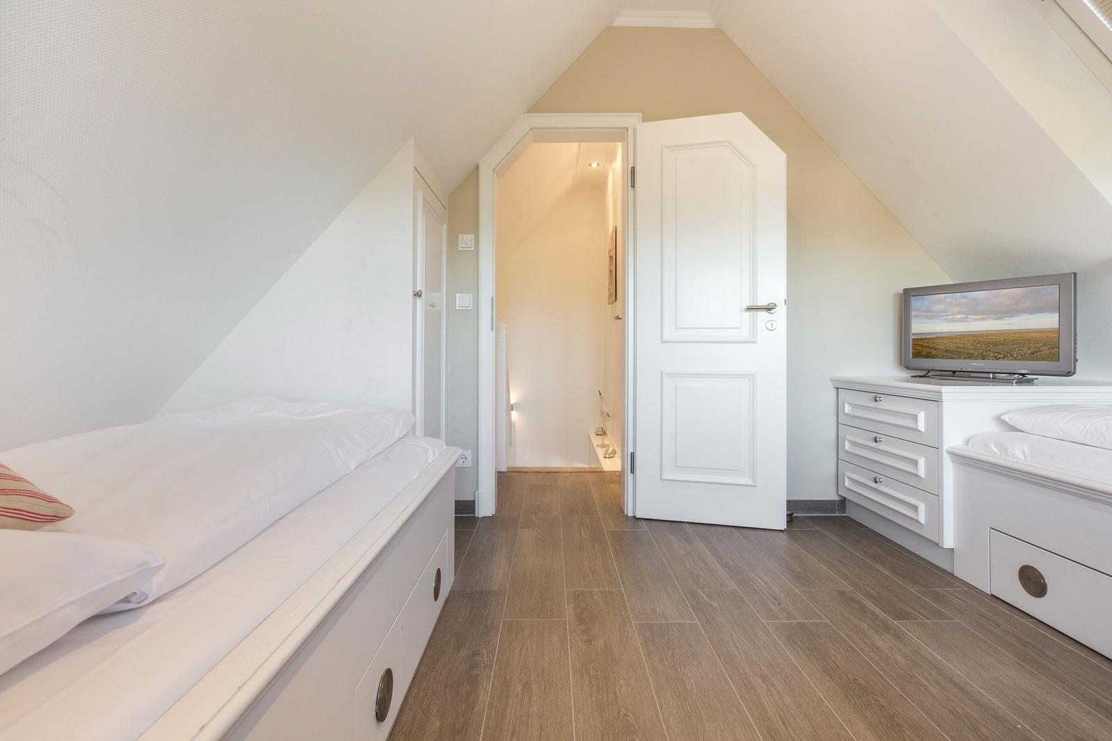 Bedroom with sloped ceiling, bed, dresser, and TV