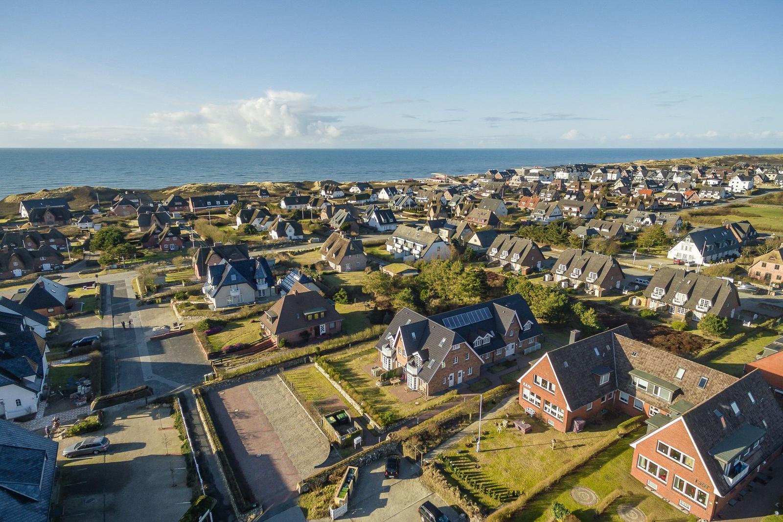 Aerial view of coastal village with houses and ocean in background.