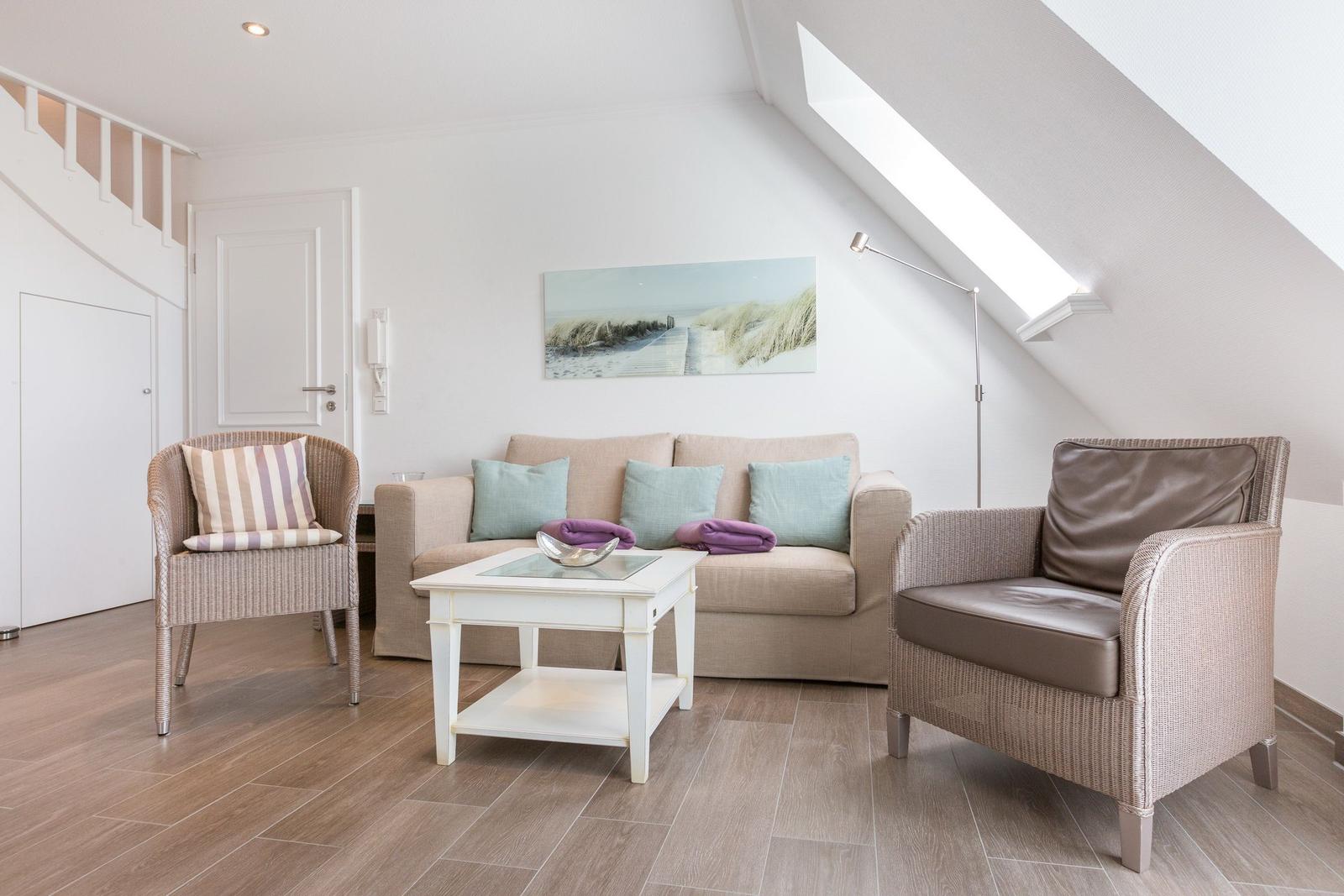 Living room with sofa, two chairs, and glass-top table under sloped ceiling.
