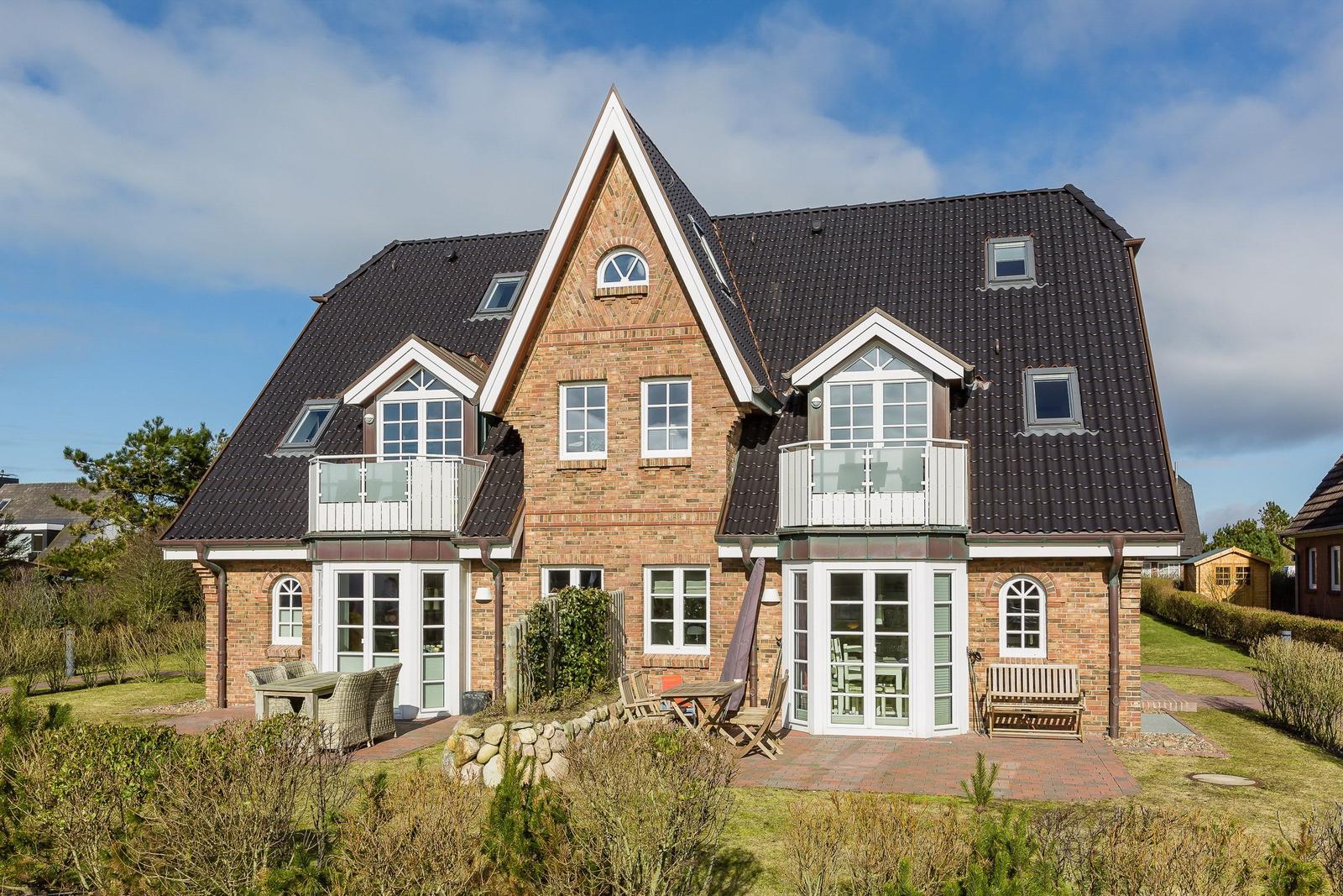 Two-story house with balcony, terrace, and garden.