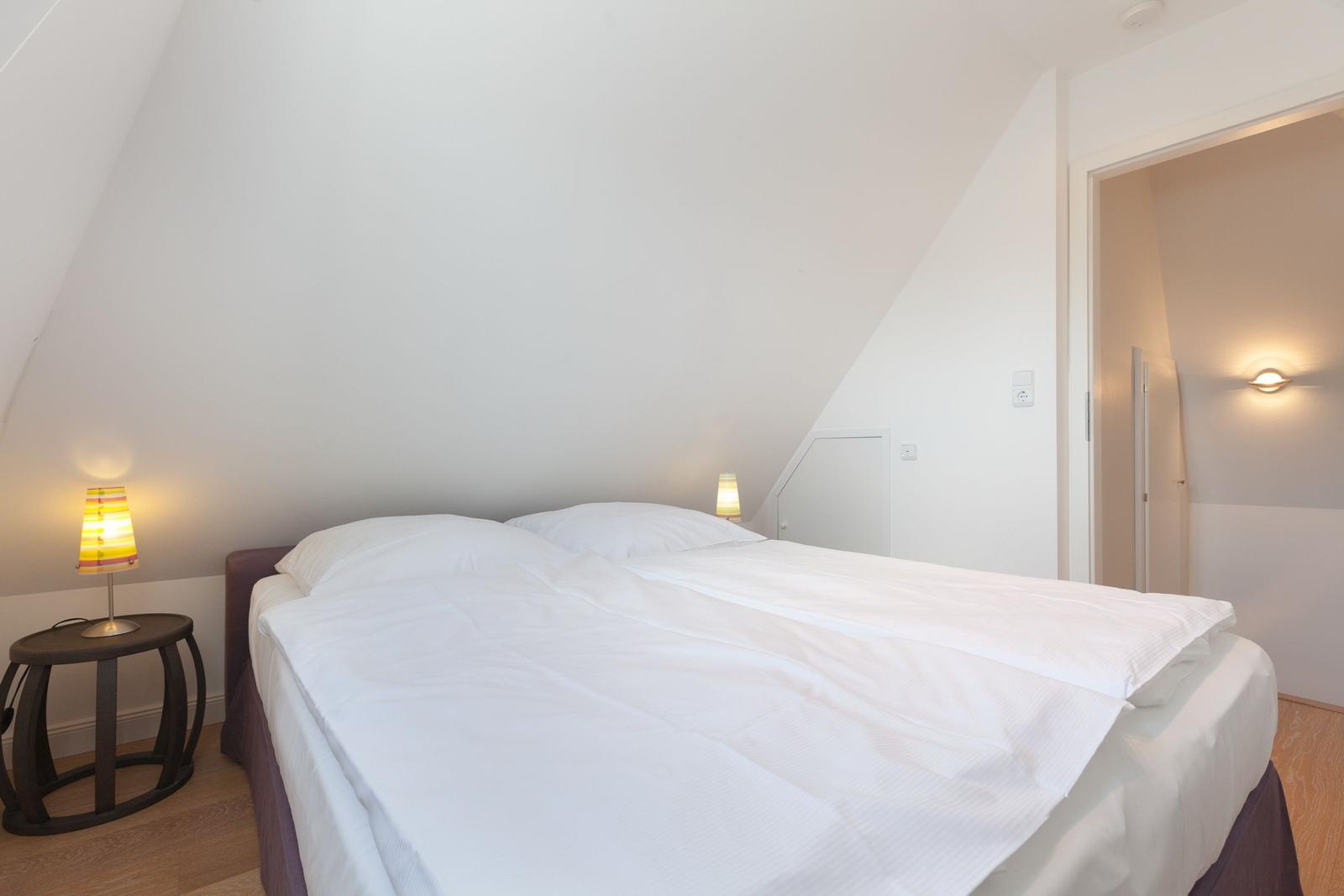 Schlafzimmer mit Doppelbett und zwei Nachttischen mit Lampen.