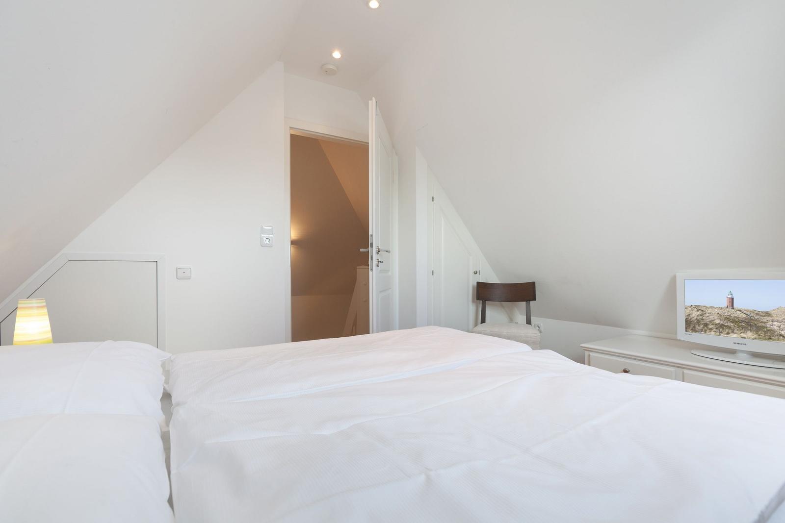 Schlafzimmer mit Doppelbett, Schreibtisch und Fernseher