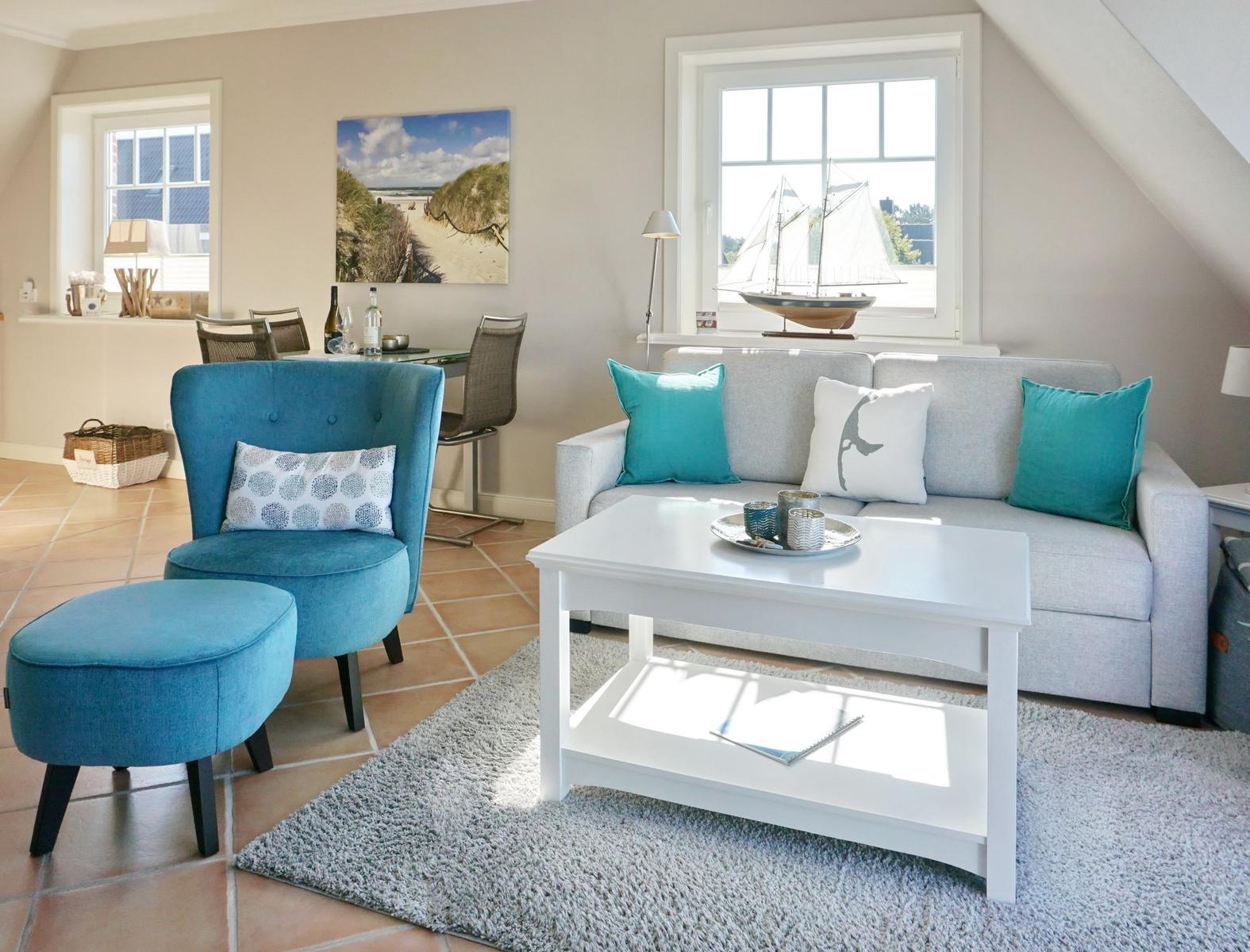 Wohnzimmer mit Sofa, blauer Sessel und Fenster mit Segelboot.