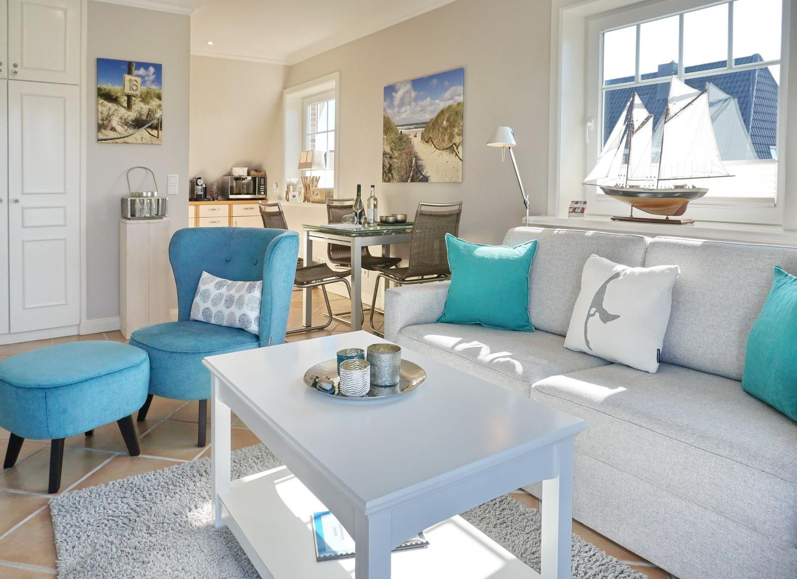Wohnzimmer mit Sofa, blauer Sessel und Essbereich