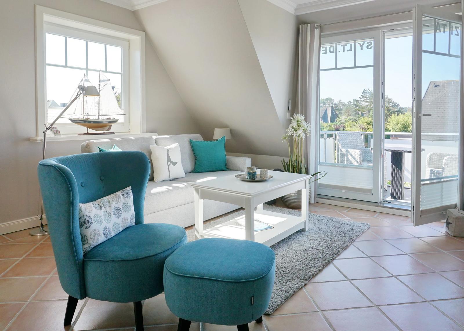 Ein Wohnzimmer mit blauer Sitzgelegenheit, Sofa und Terrasse.