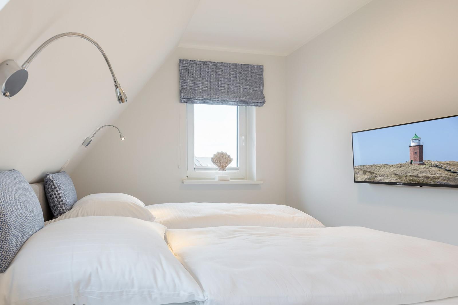 Schlafzimmer mit Doppelbett, Fenster und Wandbild mit Leuchtturm.