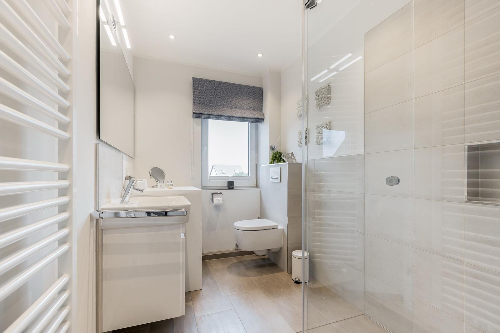 Moderne Badezimmer mit Dusche, Waschbecken und Toilette.
