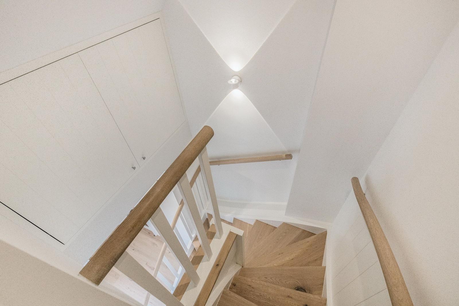 Hölzerner Treppenaufgang mit weißer Treppe und Handläufen
