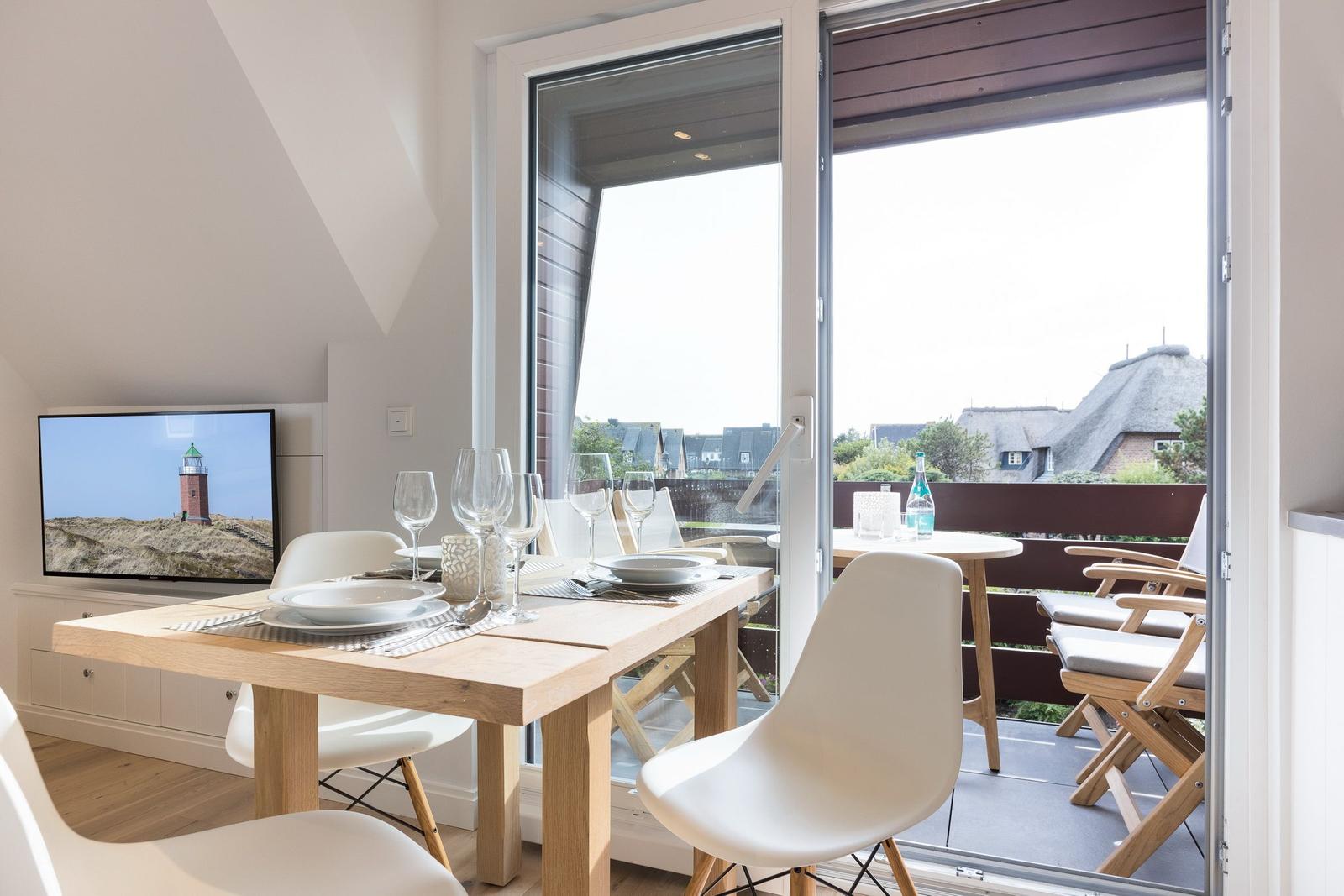 Essbereich mit Tisch und Stühlen, Blick auf Balkon mit Sitzgelegenheiten.