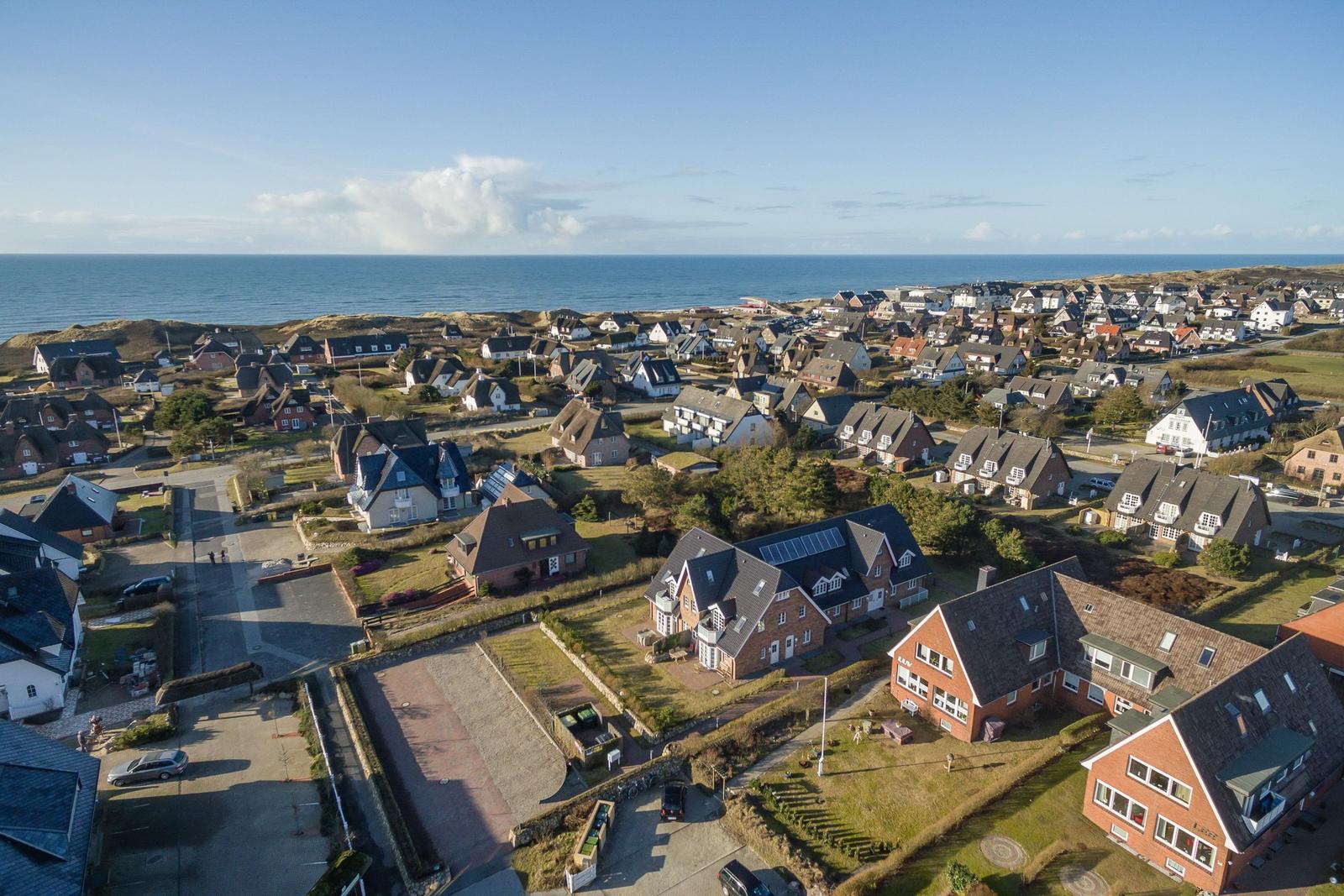Aerial view of a coastal village with houses and the sea in the background.