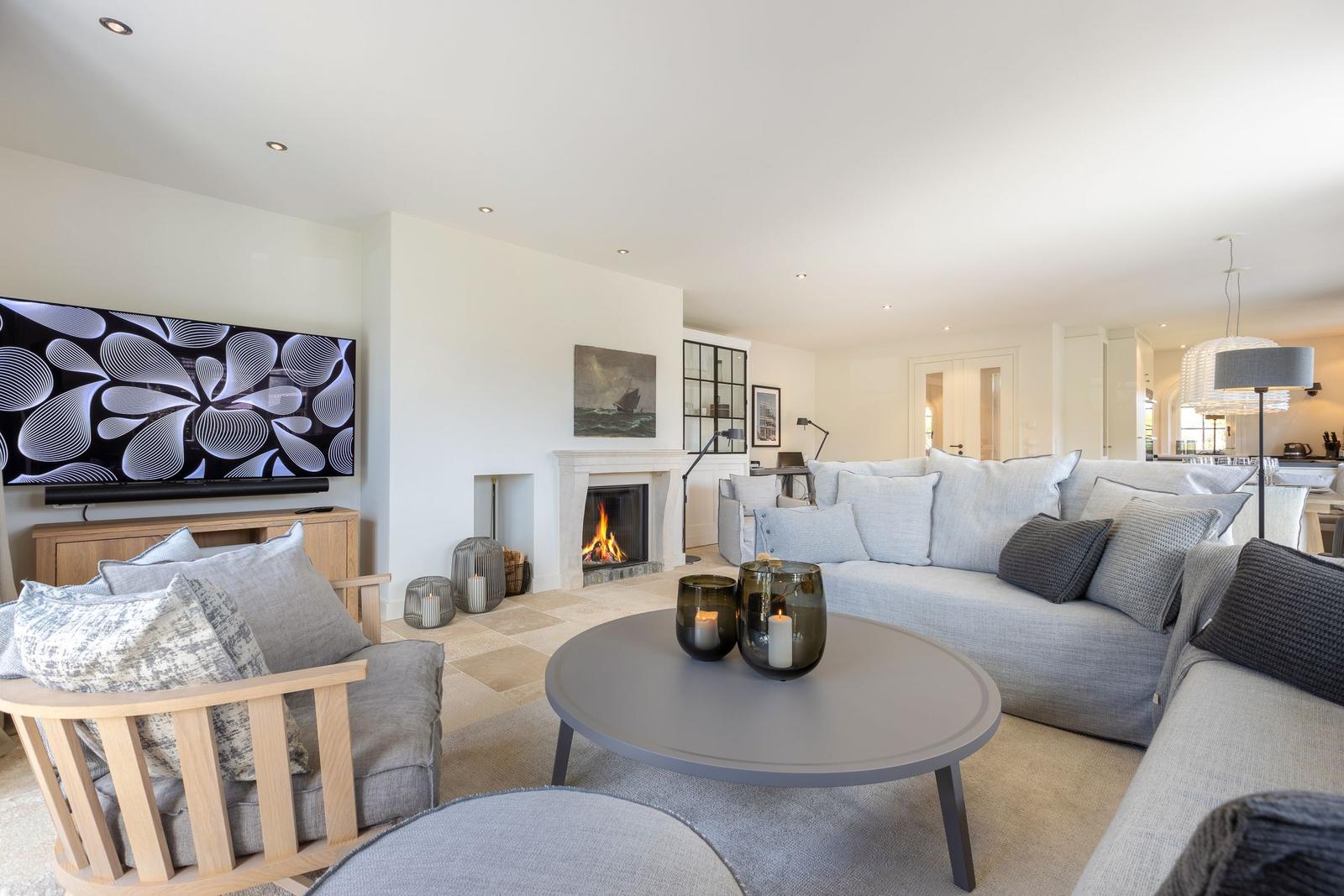 Living room with fireplace, sofa, and TV. Round coffee table and decorative candles.