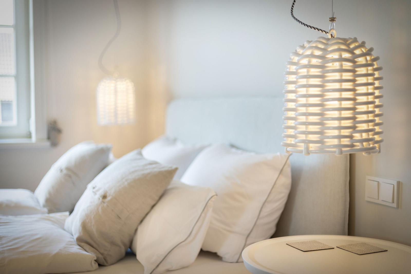 Bedroom with bed, pillows, and hanging lamps.