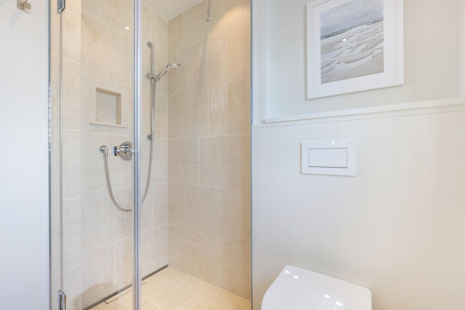 Shower with glass door, toilet, and wall picture