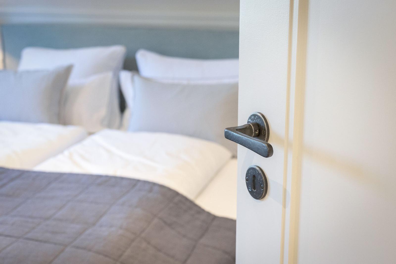 Door handle opens bedroom with bed and pillows.