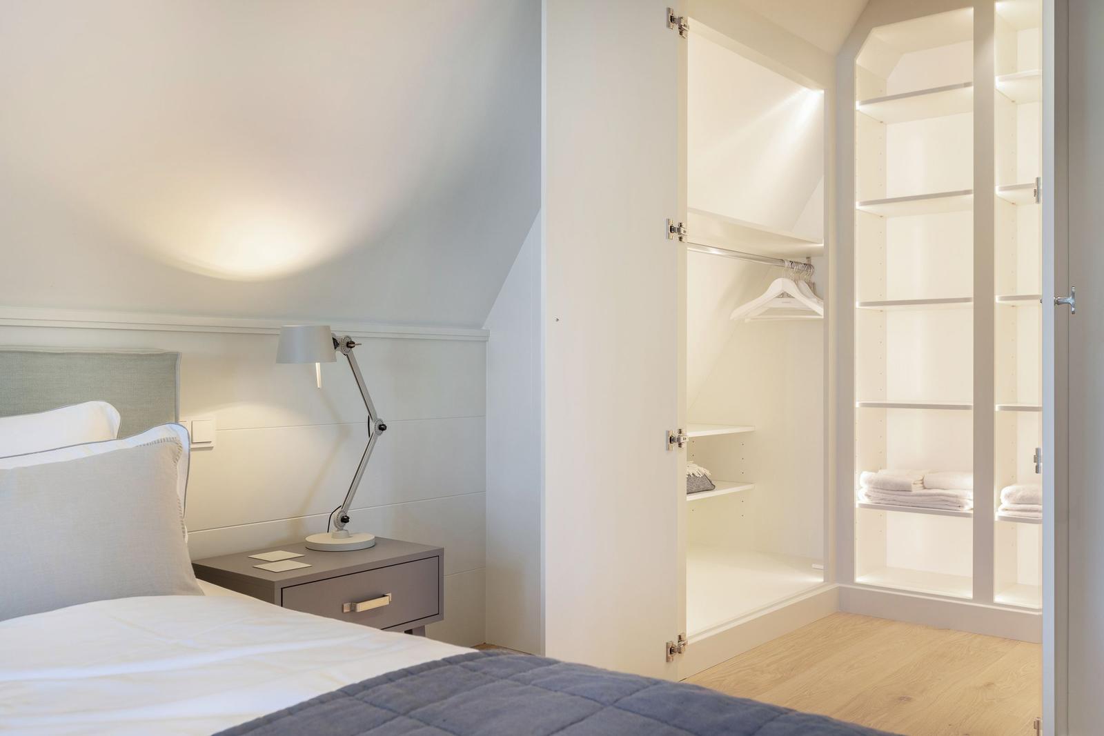 Bedroom with bed, nightstand, and wardrobe with shelves.