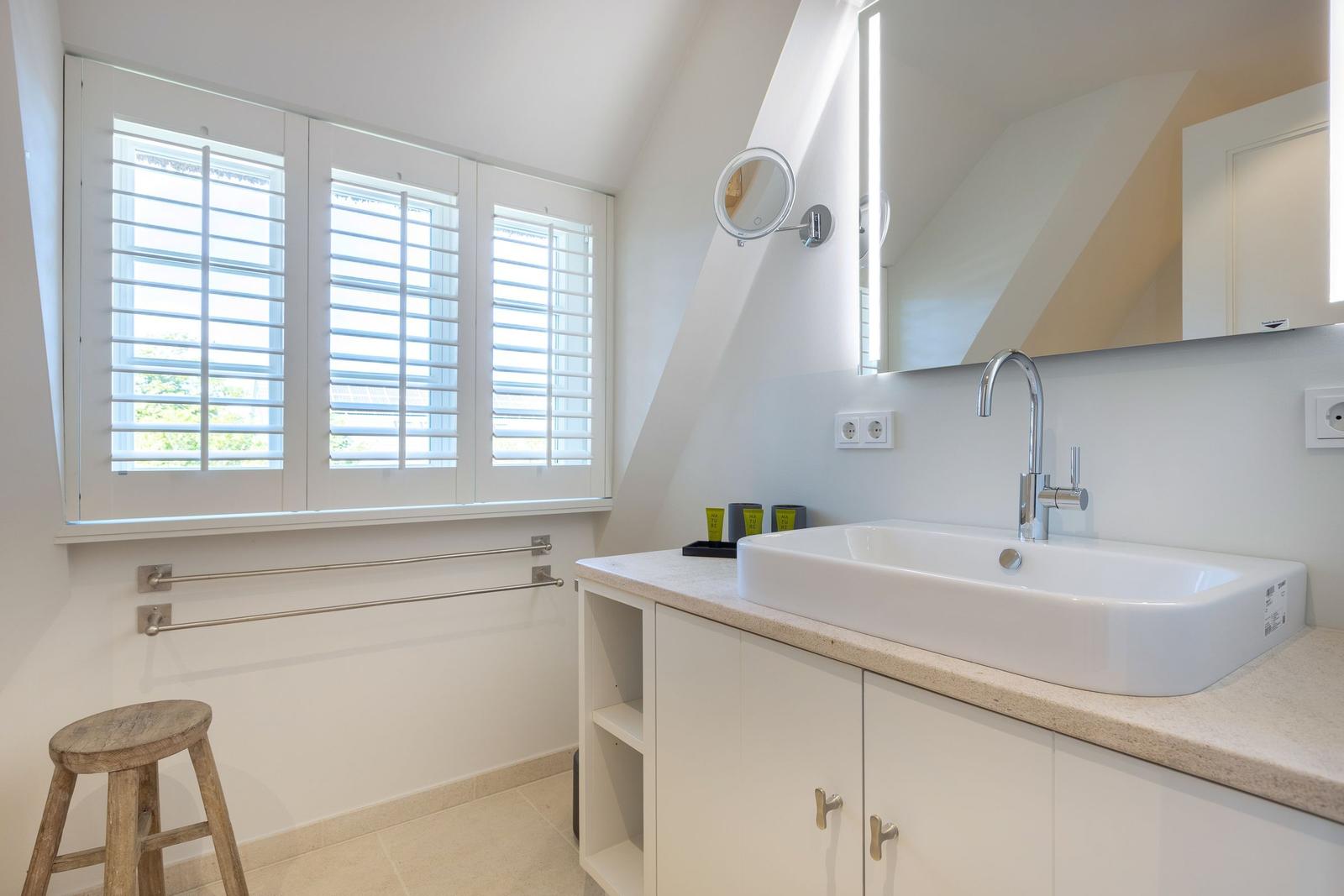 Bathroom with sink, mirror, and window with blinds.