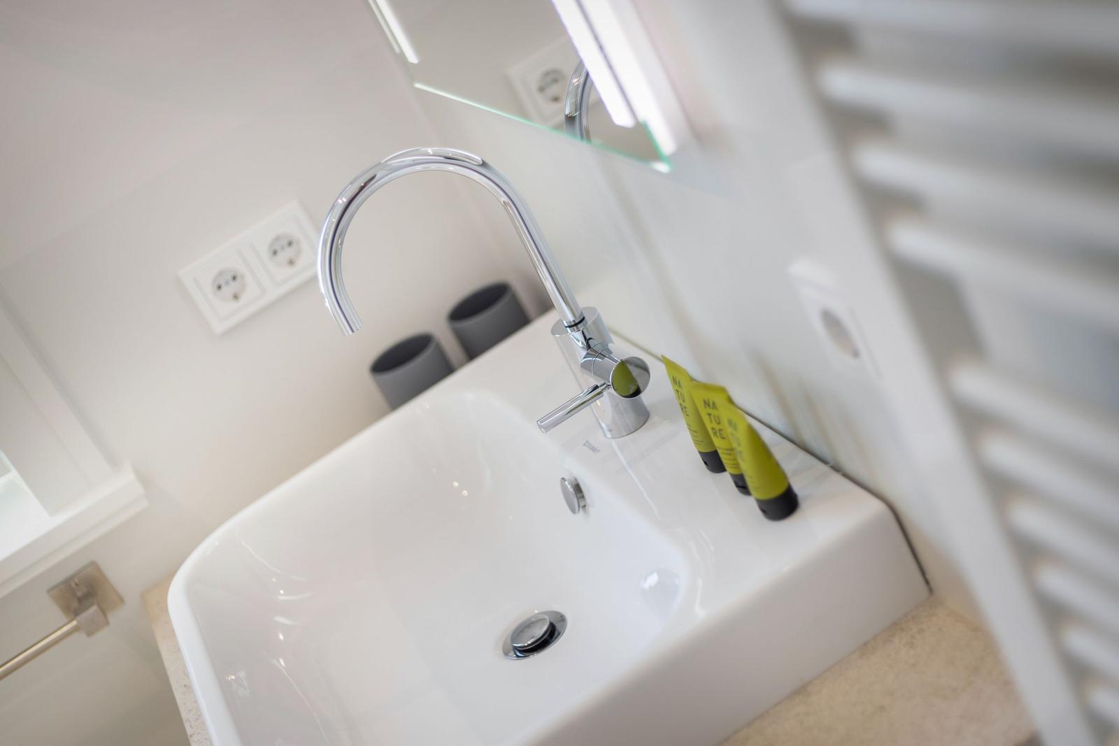 Modern sink with chrome faucet and mirror cabinet.