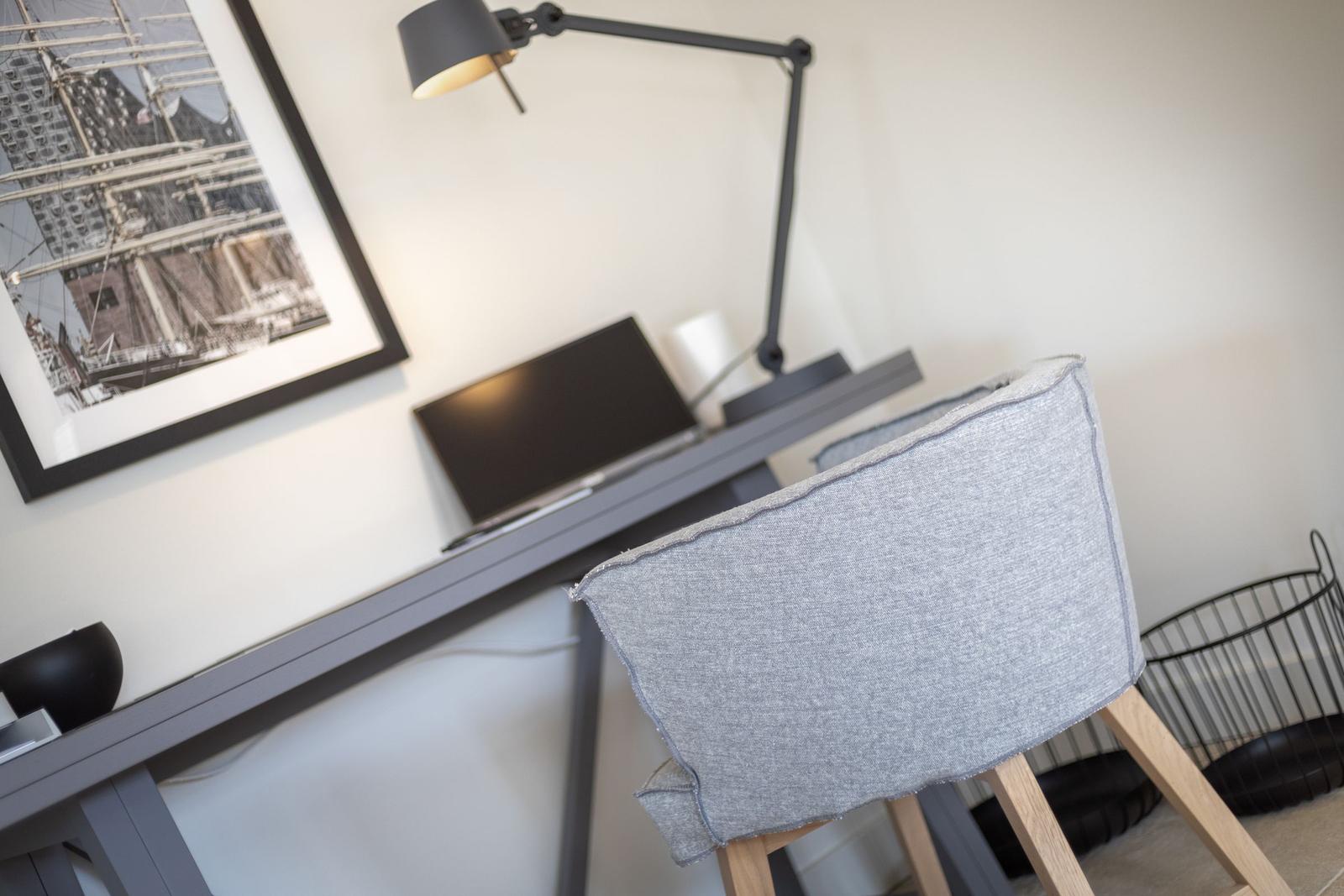 Desk with chair, lamp, and picture on the wall.
