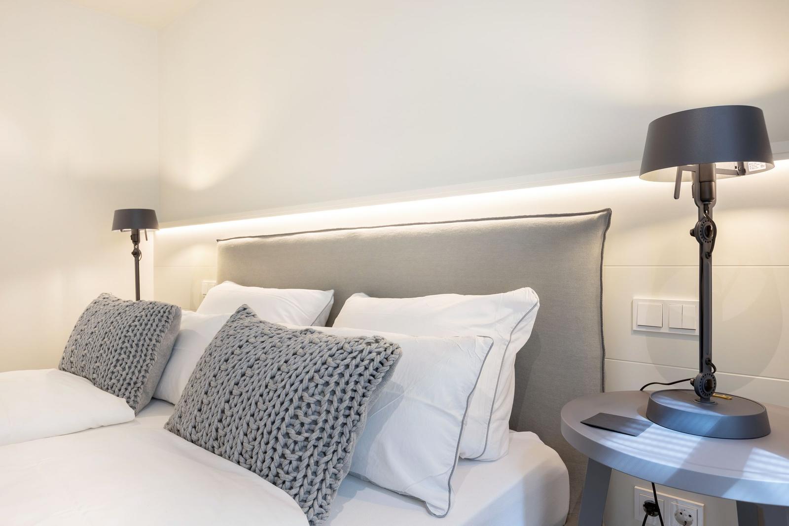 Bedroom with bed, pillows, and nightstand with lamp.