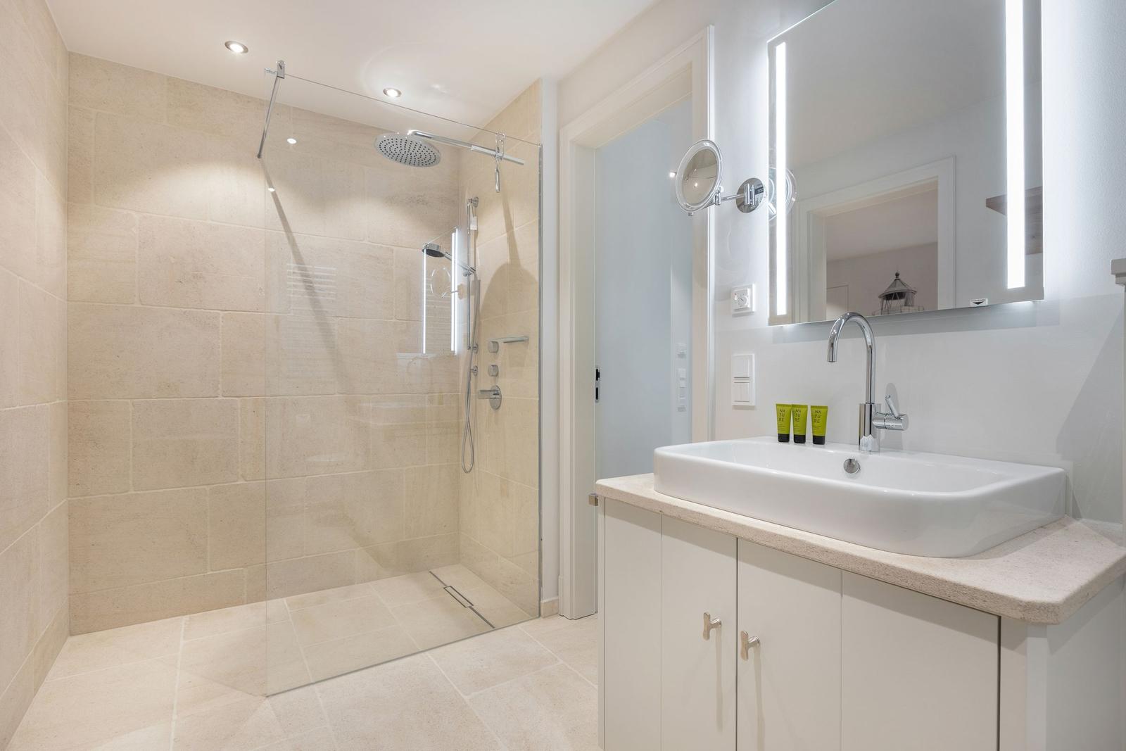 Bathroom with shower, sink, and lit mirror.