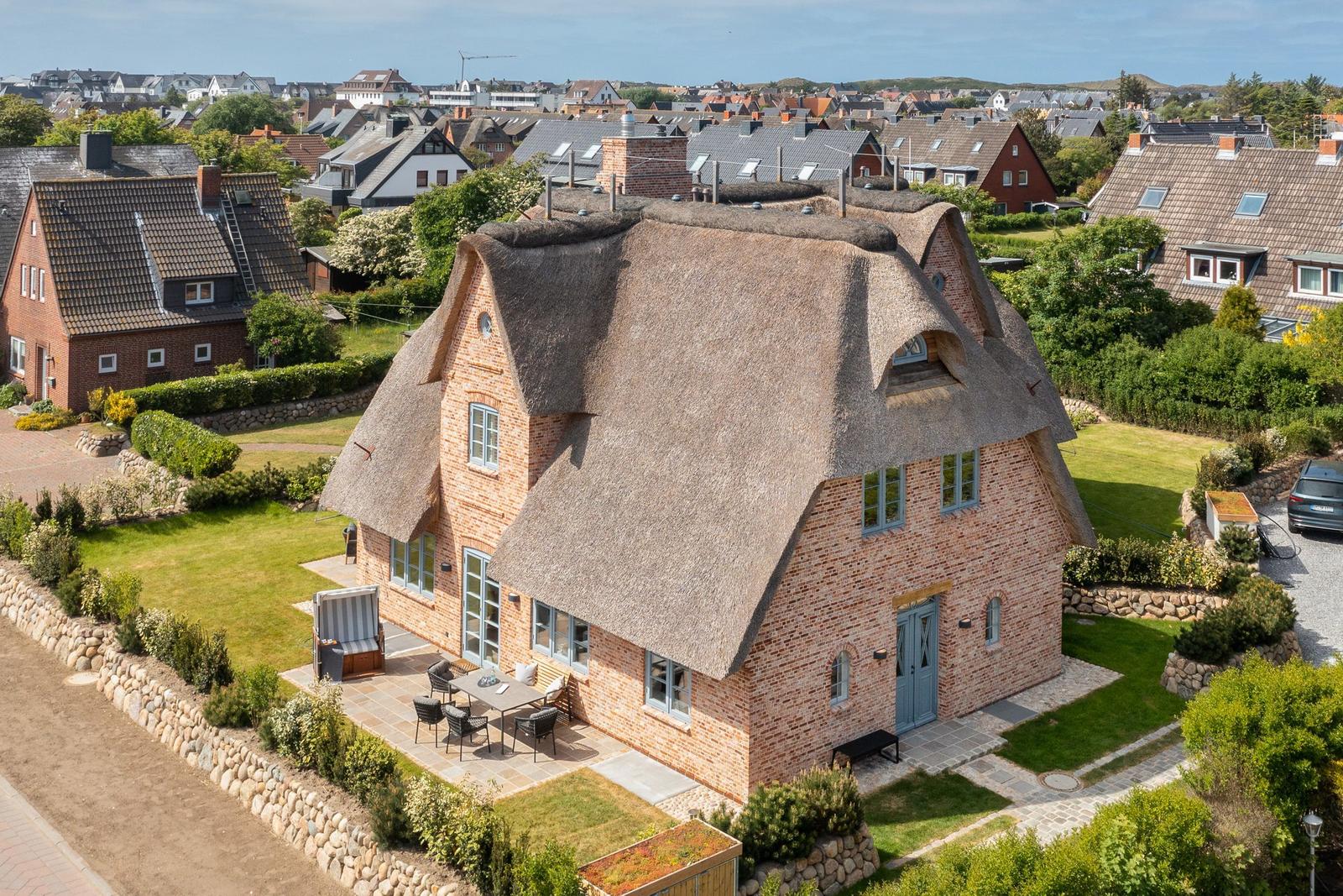 House with thatched roof and garden, view of town