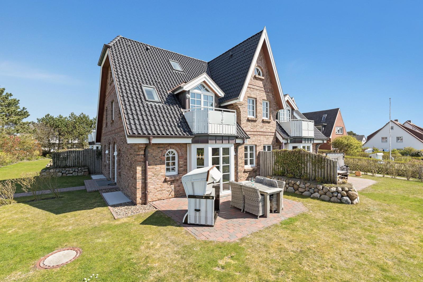Haus mit Terrasse, Grill und Garten. Dachterrasse und Holzgeländer sichtbar.