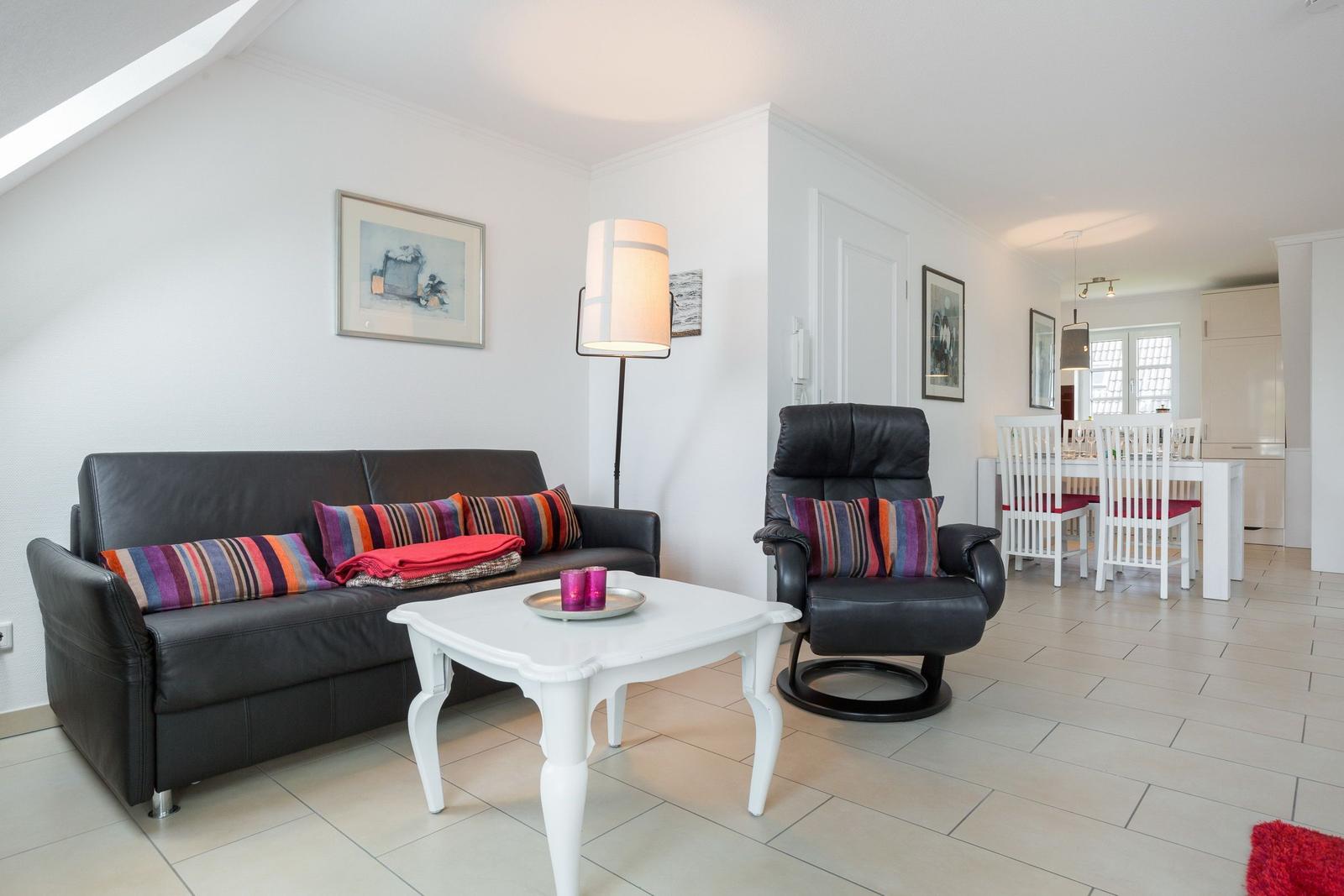 Wohnzimmer mit Sofa, Sessel und Esstisch im Hintergrund.