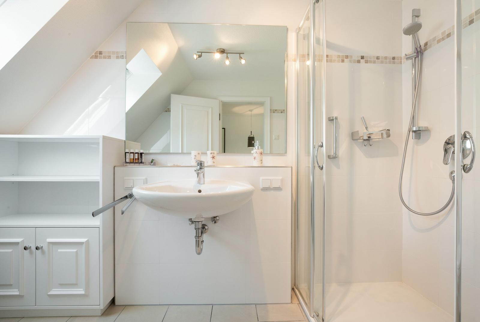 Badezimmer mit Dusche, Waschbecken und Spiegel unter Dachschräge