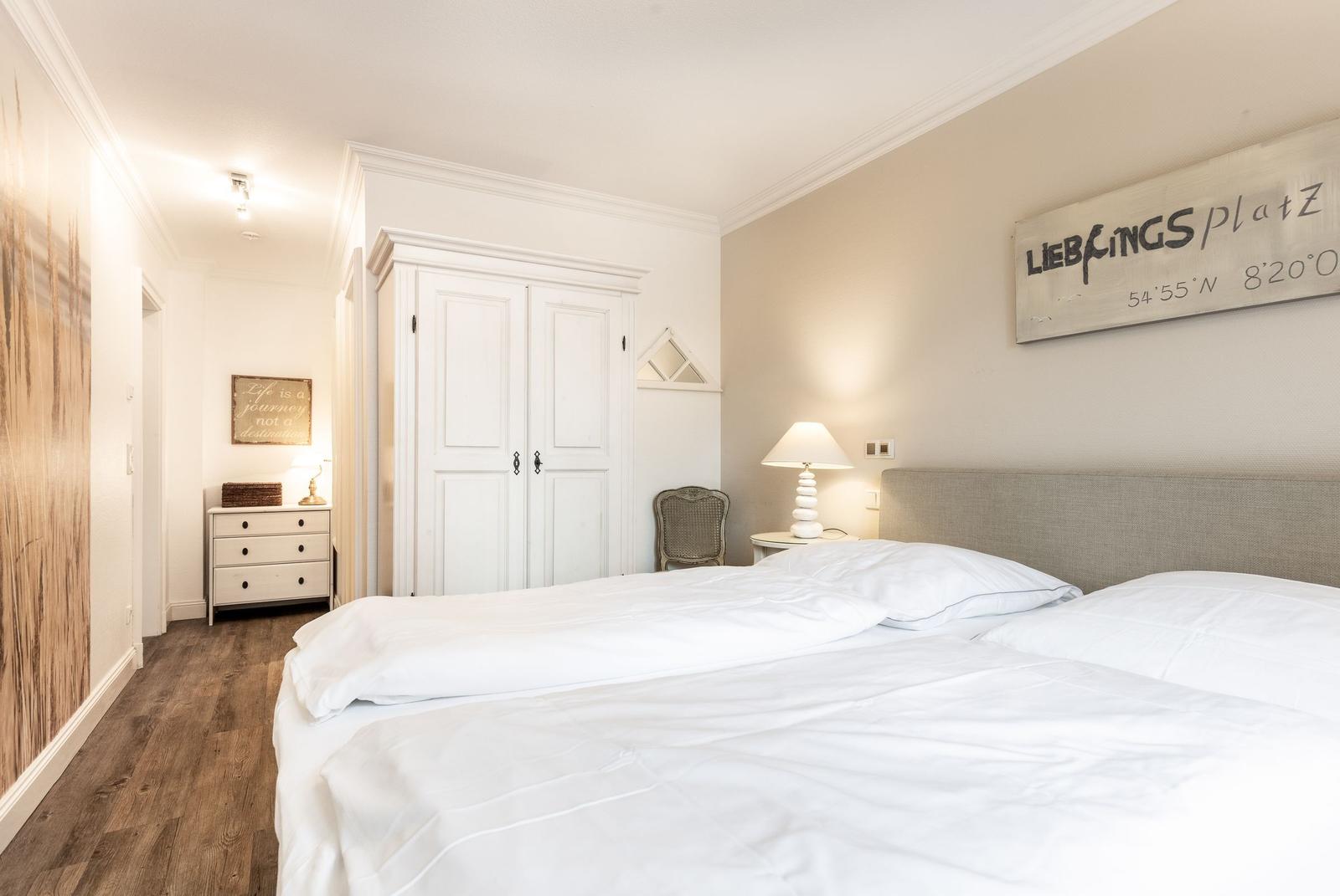 Bedroom with double bed, white closets, and wooden floor.