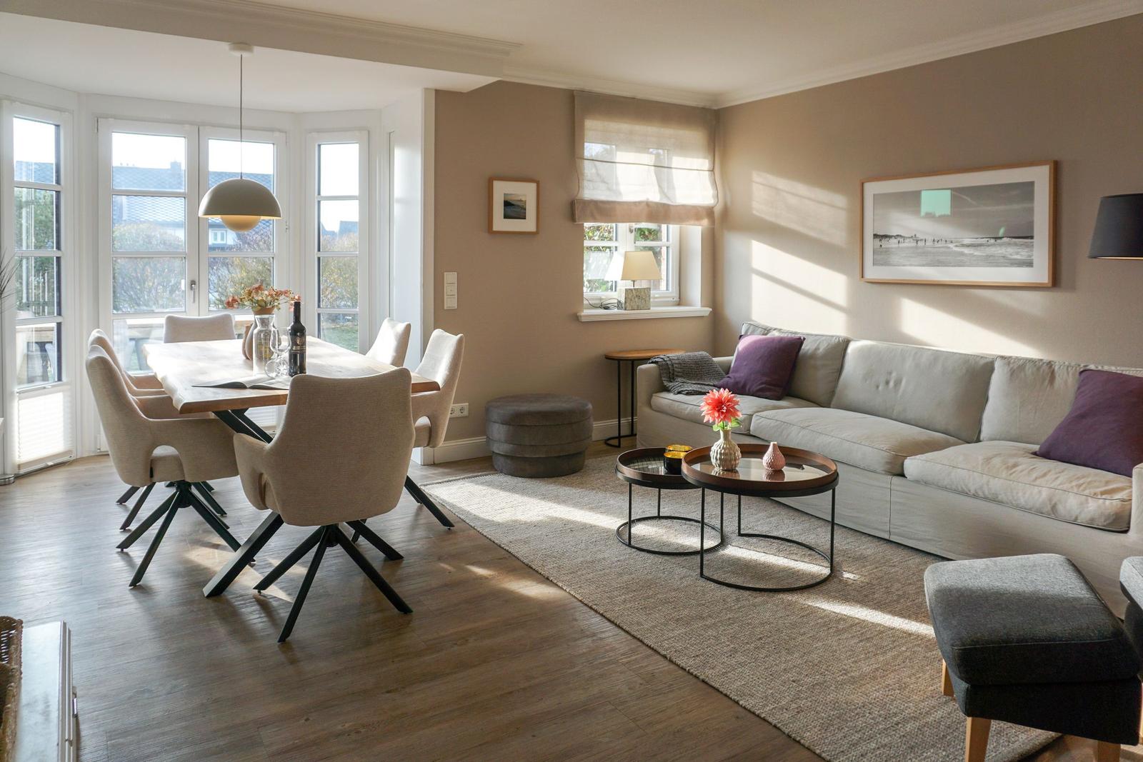Living and dining area with sofa, table and chairs. Large windows and light walls.