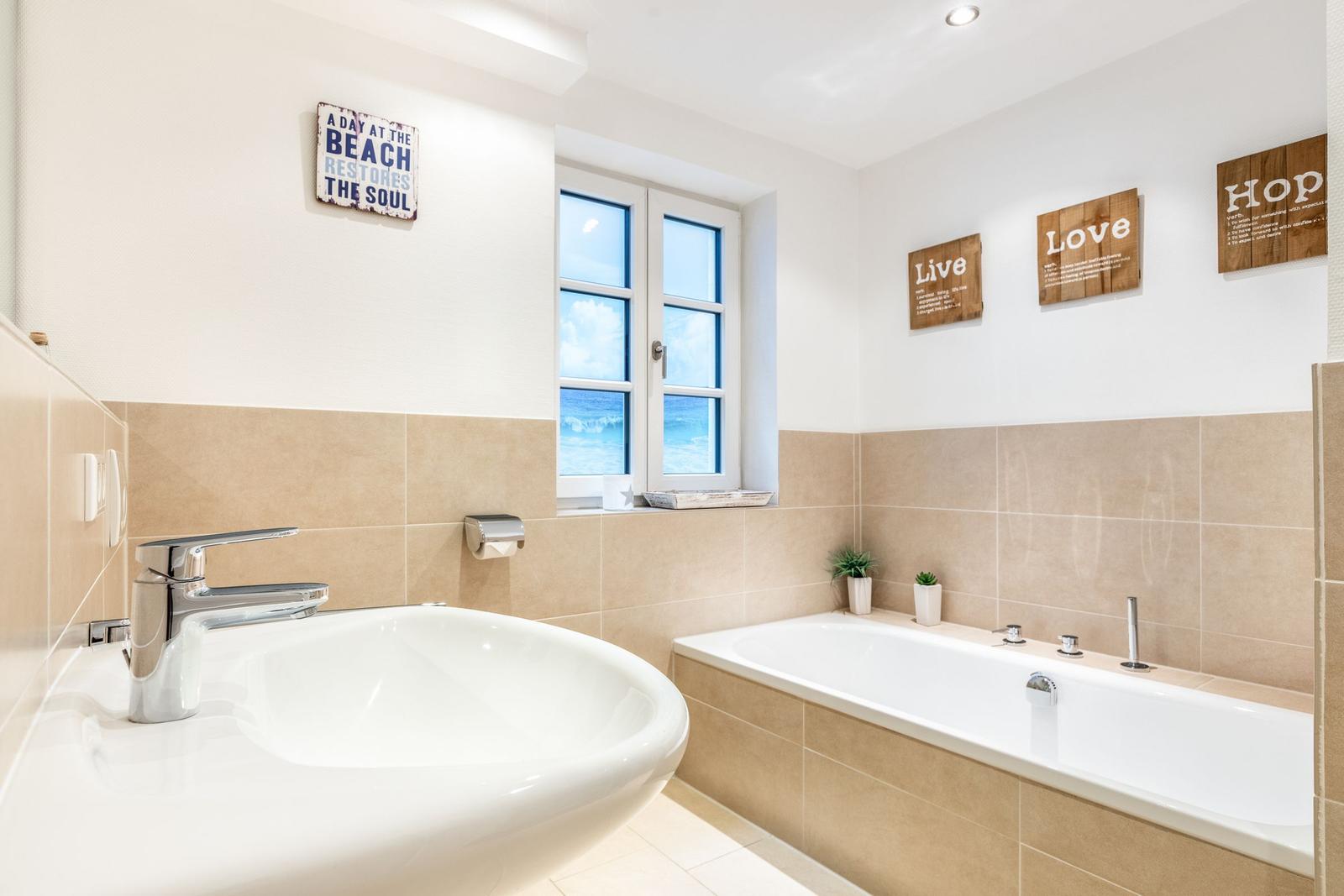 Bathroom with bathtub, sink, and window with sea view.