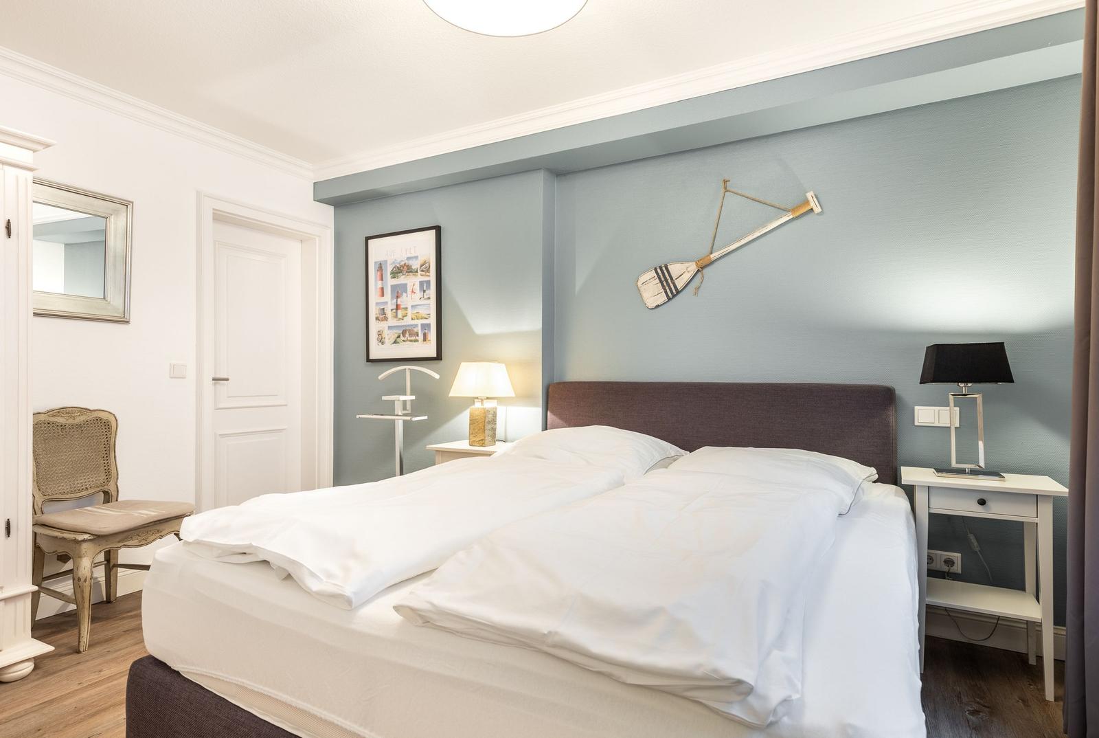 Bedroom with double bed, nightstands, and wall decor.
