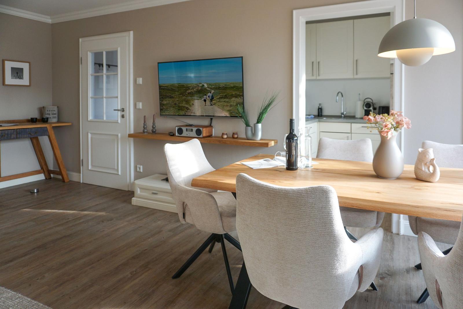Dining area with wooden table, chairs, and TV mounted on the wall.