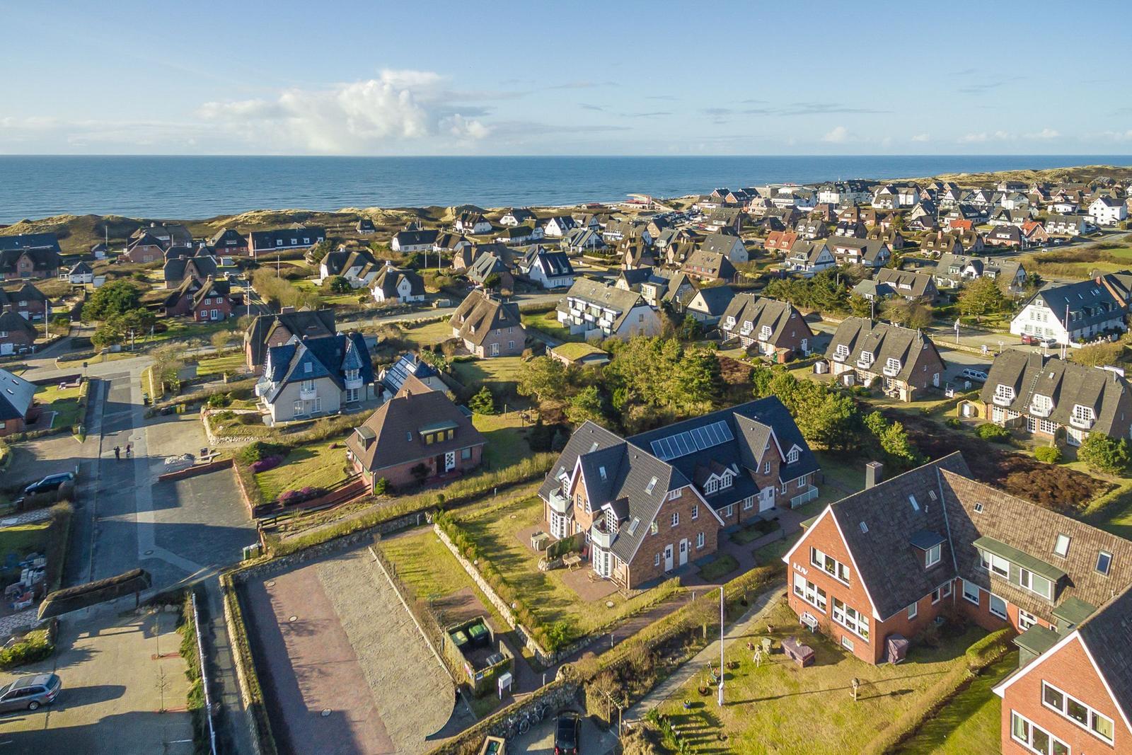 Aerial view of a coastal village with houses and the sea in the background.