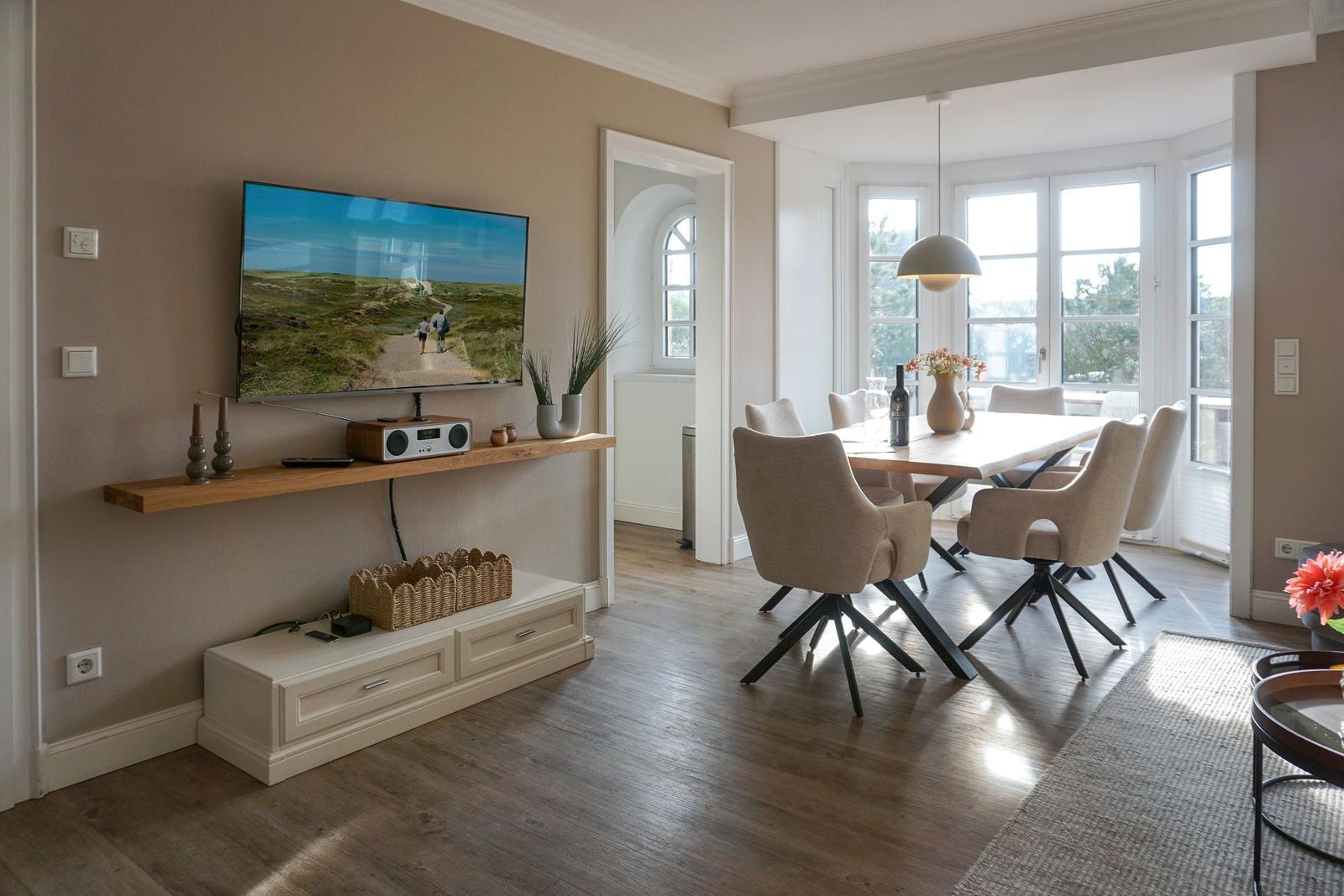 Living and dining area with TV, dining table, and windows.