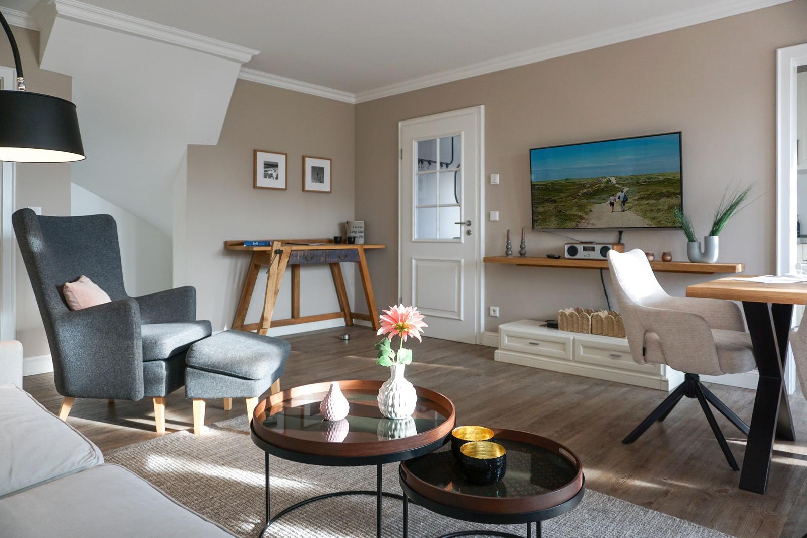Living room with armchair, table, and TV mounted on the wall.