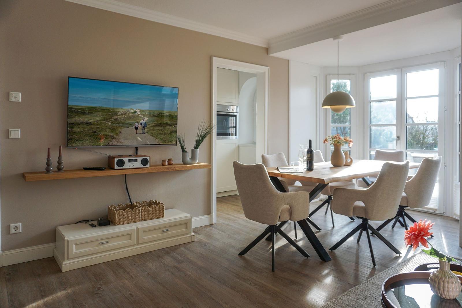 Living and dining area with TV, dining table, and windows