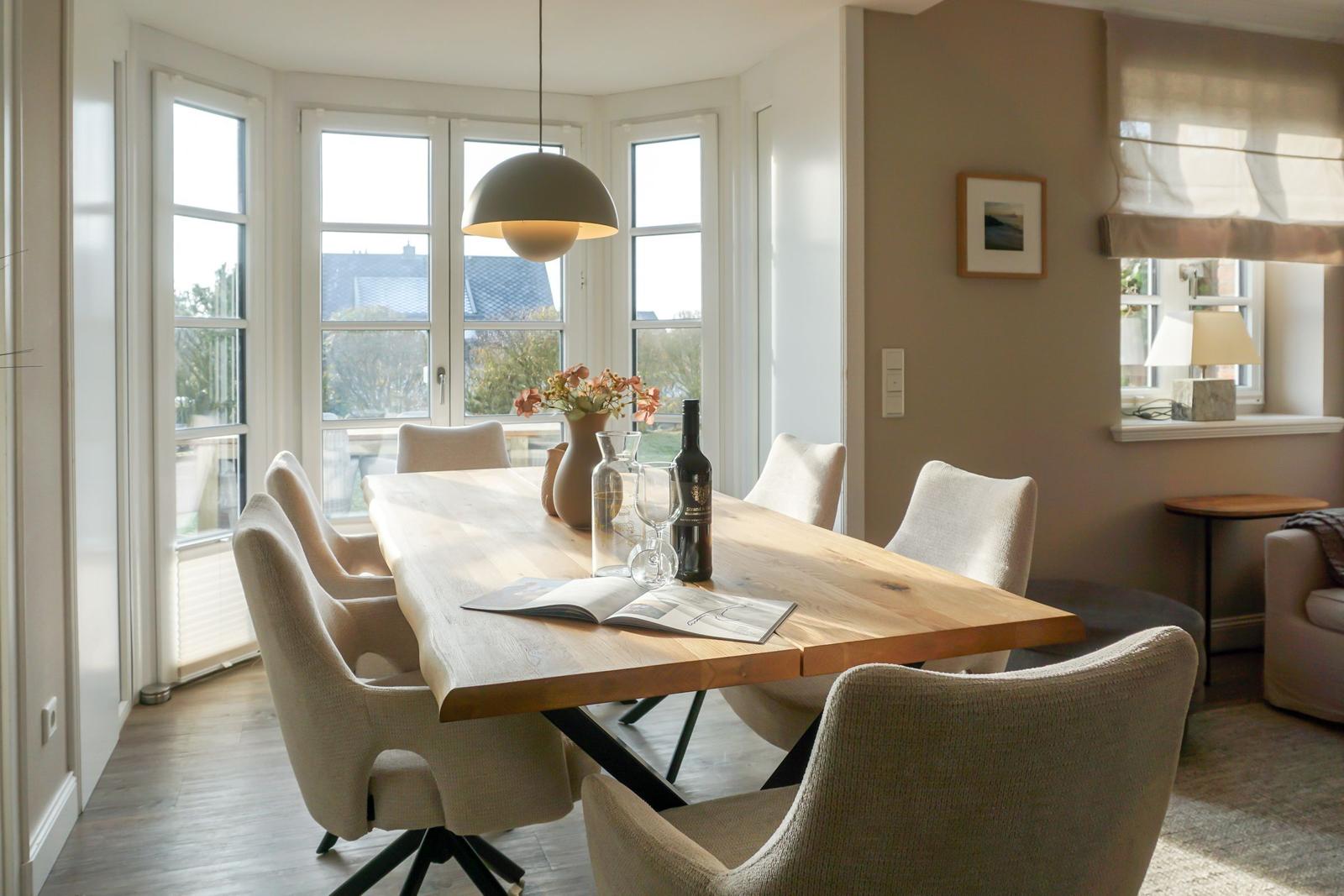 Dining room with wooden table, chairs, and window view.