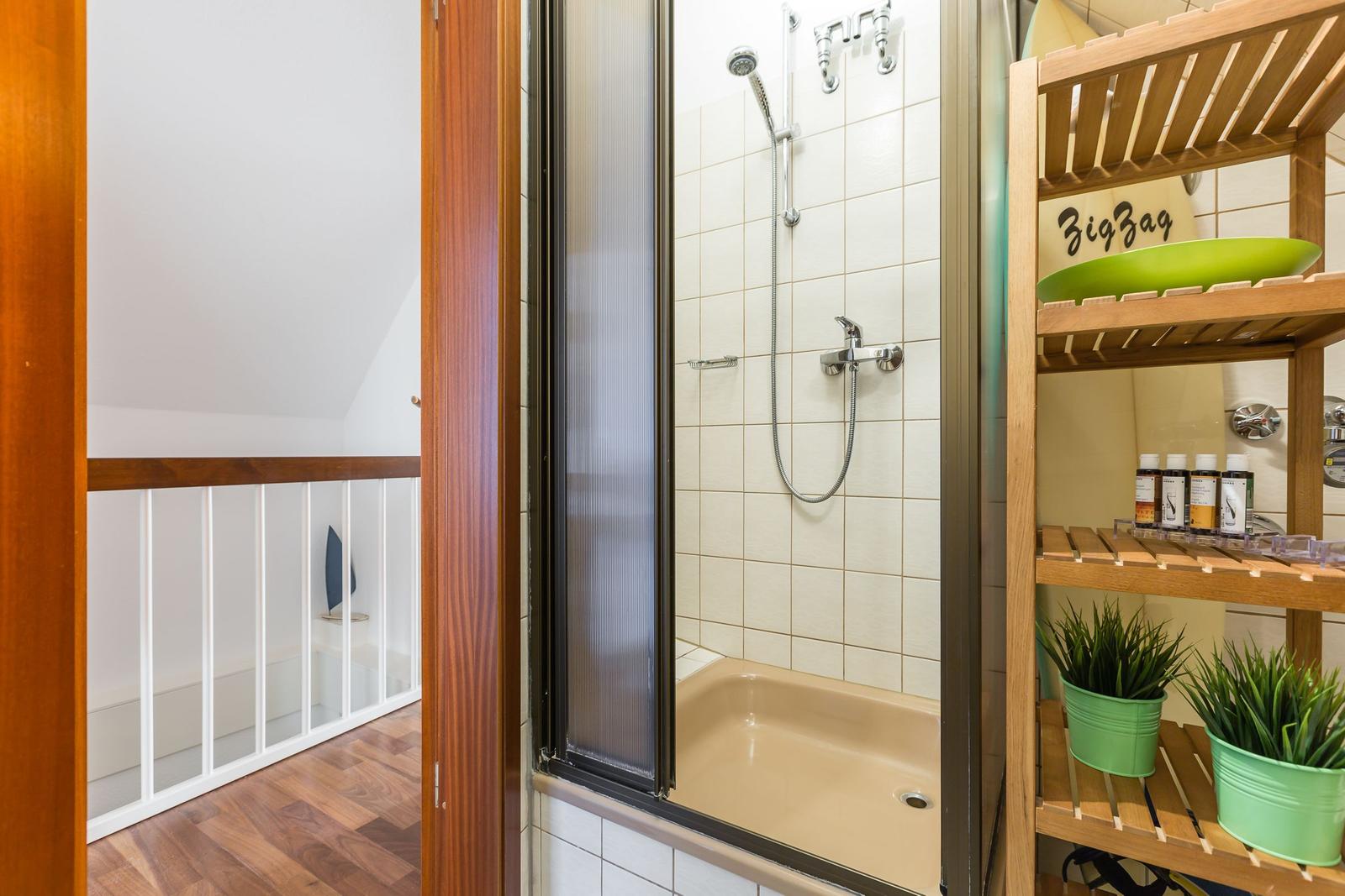 Dusche mit Glaswand, Holzregal und Pflanzen