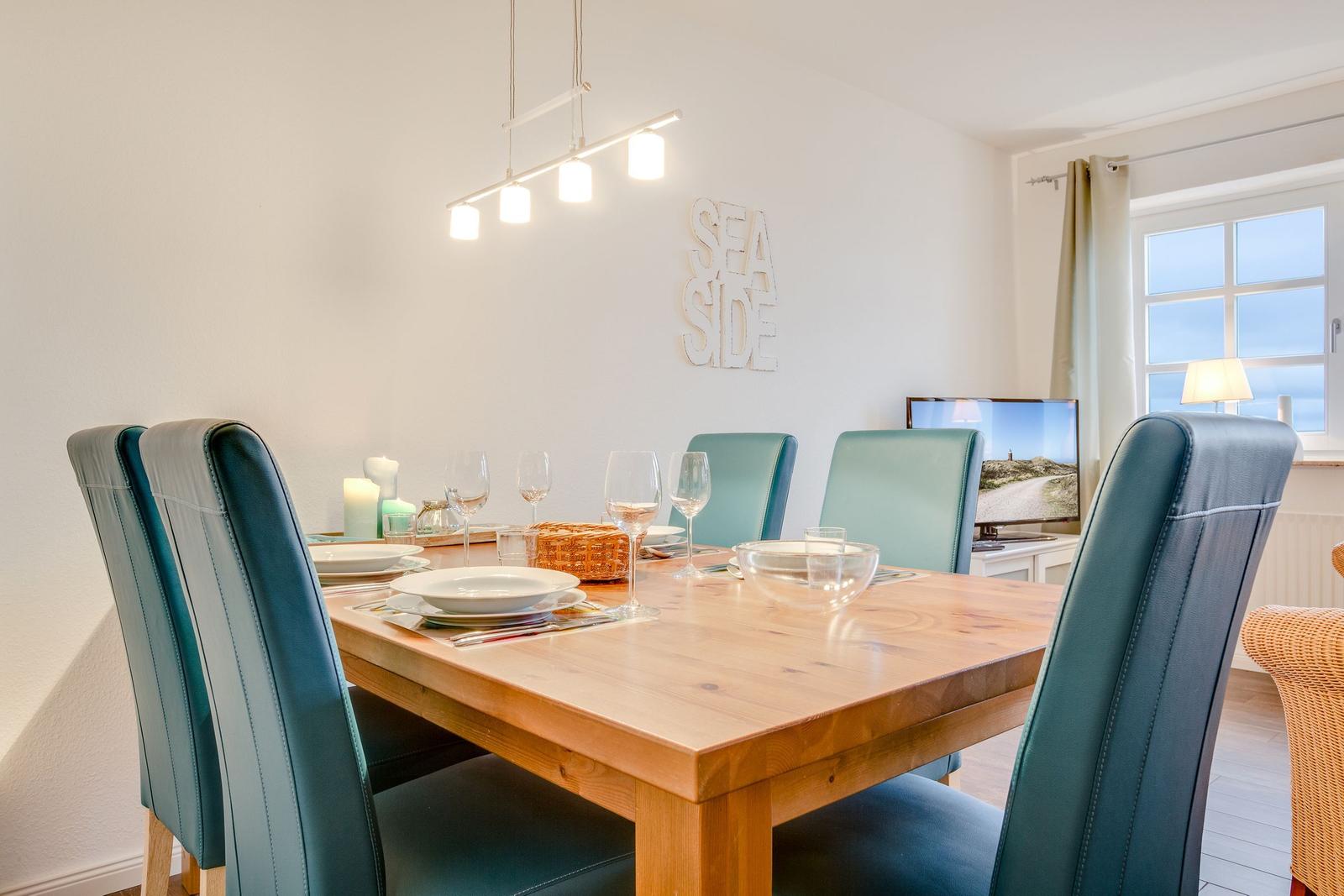 Esszimmer mit Holztisch, blauen Stühlen und Wanddekoration SEA SIDE.