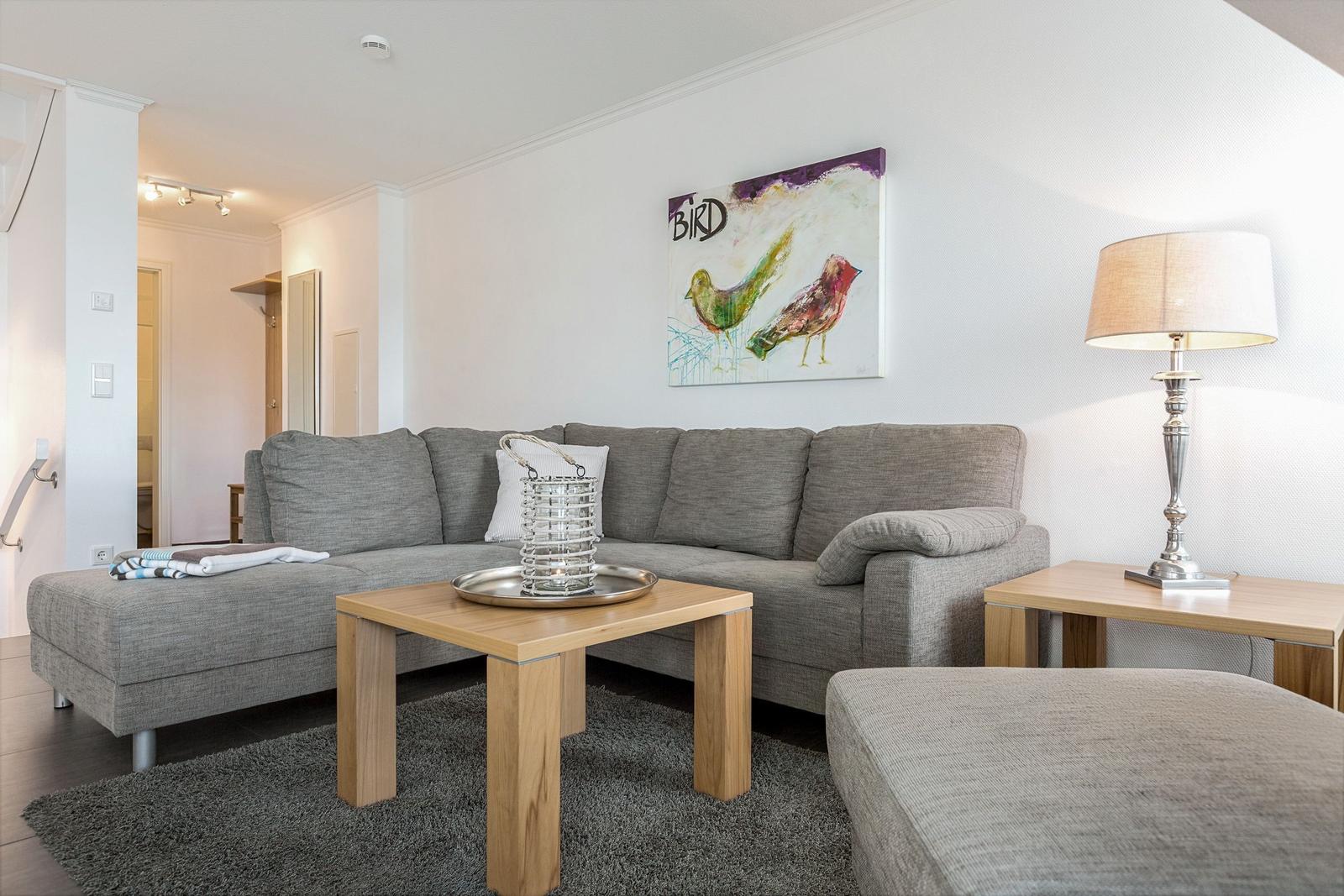 Living room with gray sofa, wooden table, and wall art with birds.