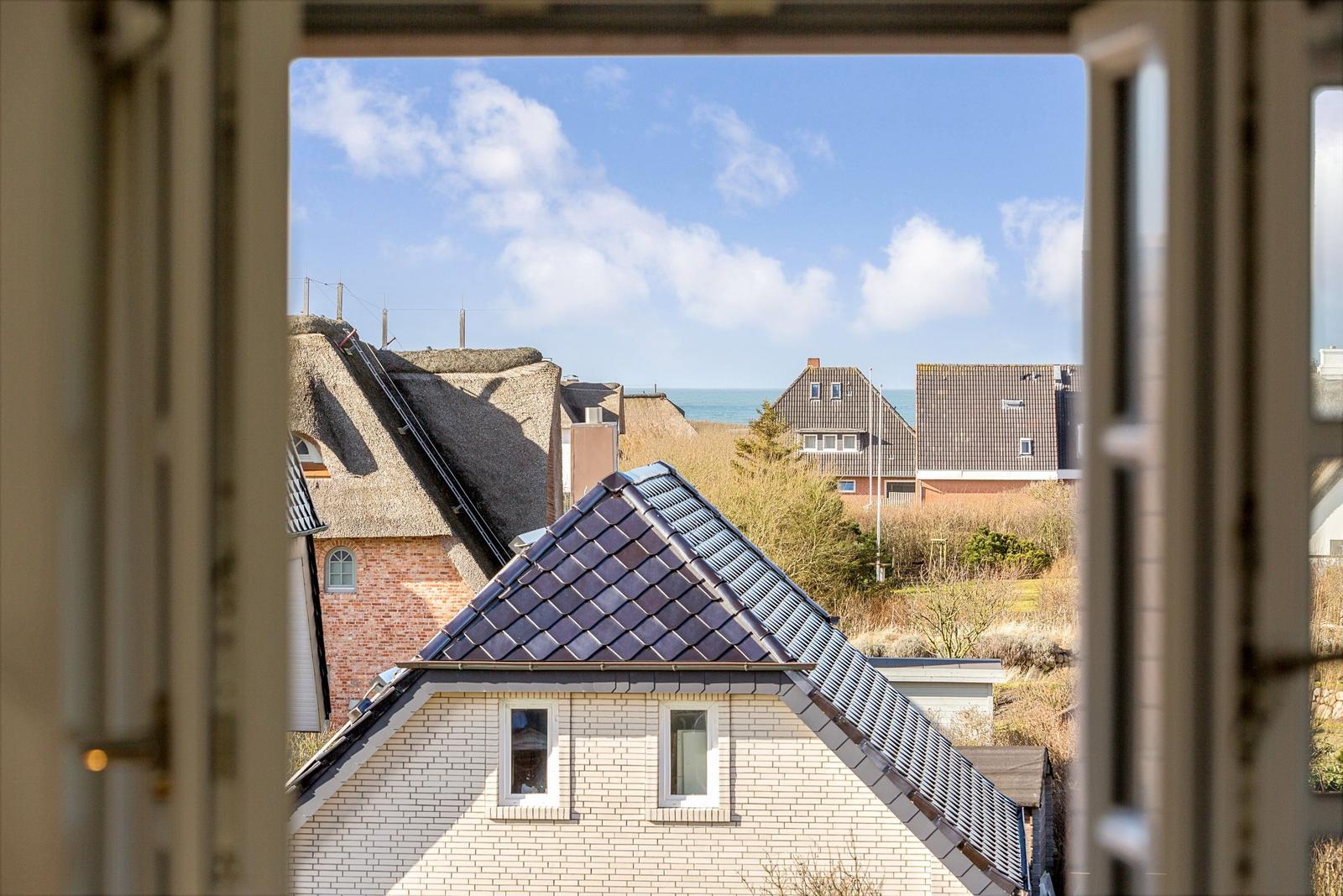 Through the window you see roofs and the sea.