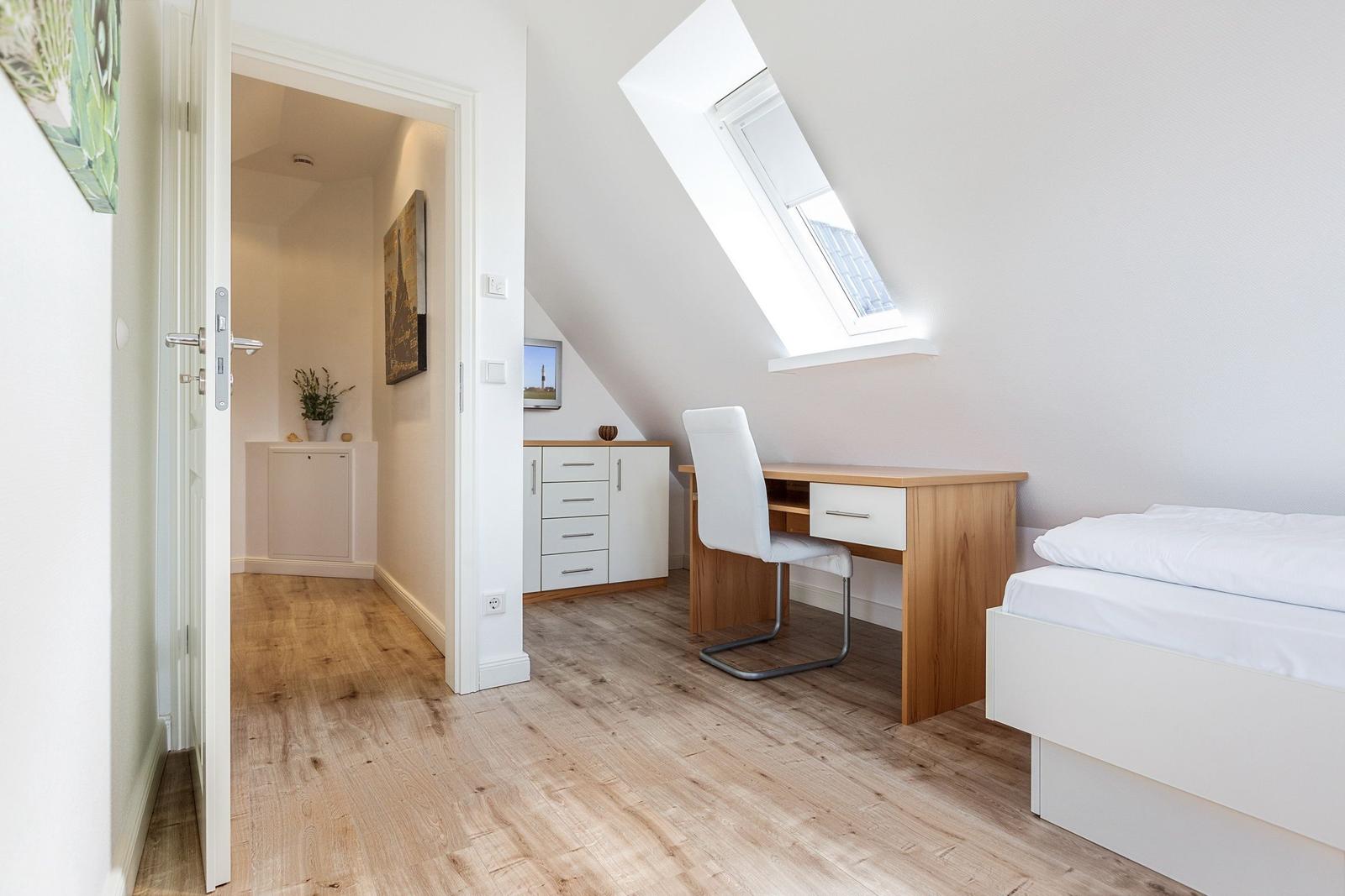 Bedroom with skylight, desk, and bed.
