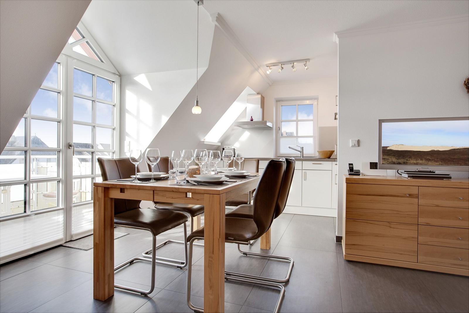 Dining room with wooden table, chairs, and windows to terrace.