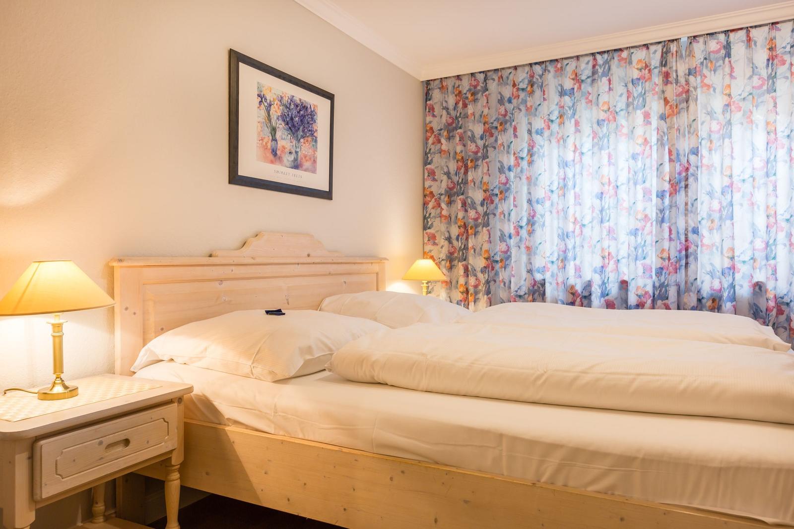 Bedroom with double bed, nightstand, and floral curtains.
