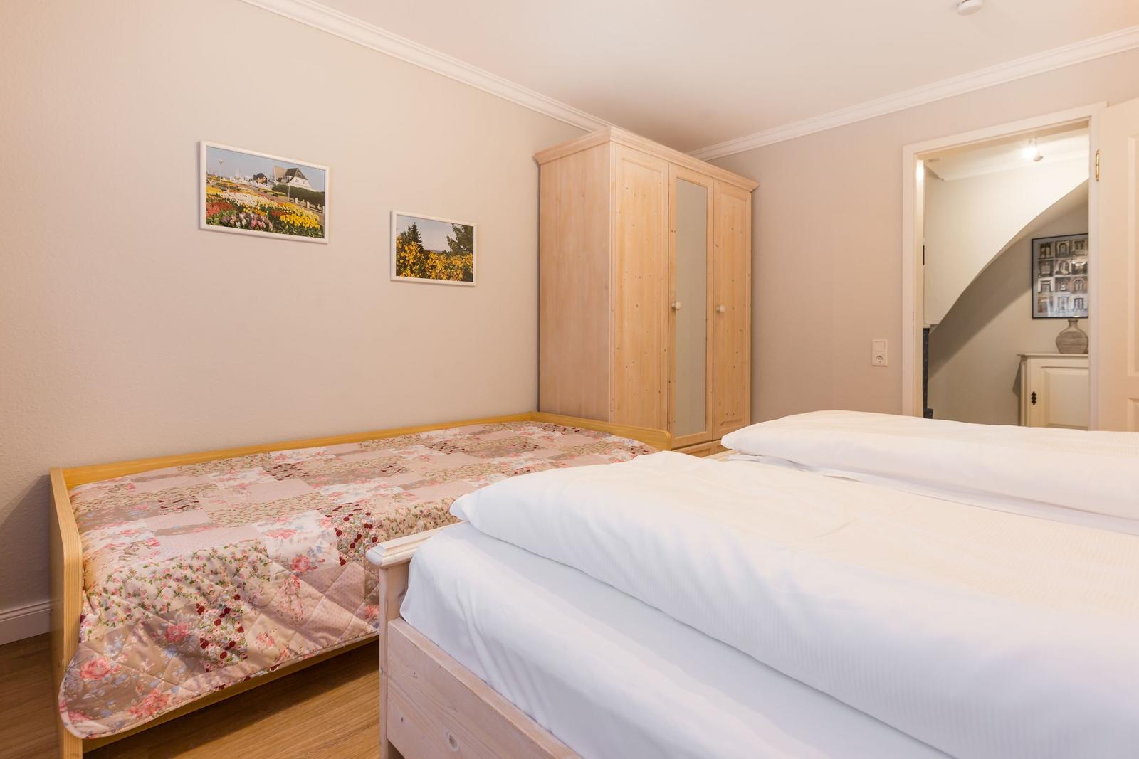 Two beds, wardrobe, and pictures on the wall.