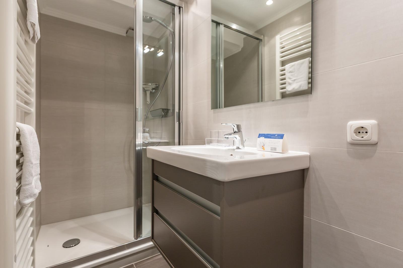 Bathroom with shower, sink, and towel rack